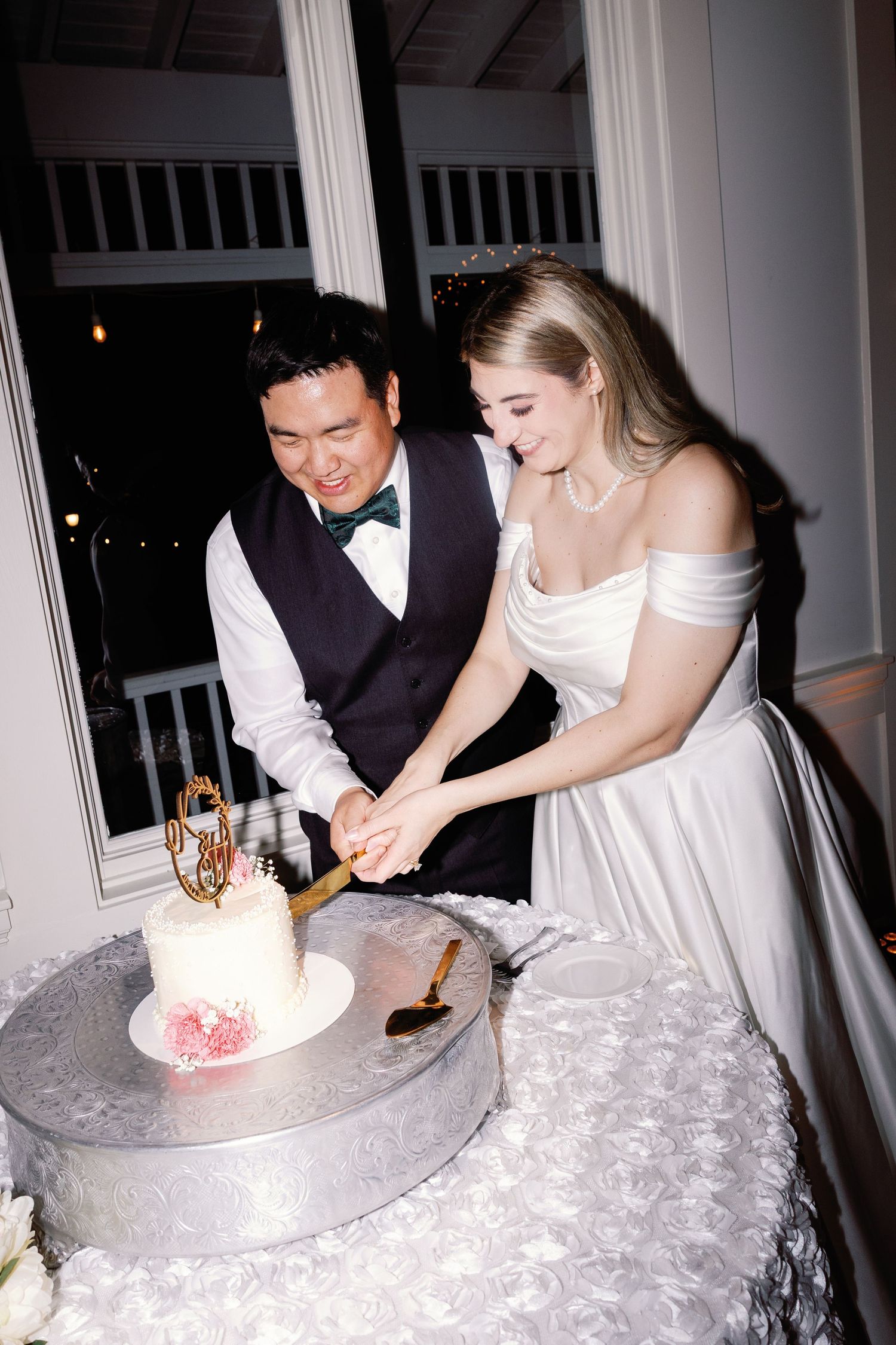 Couple cutting their white wedding cake together at the reception.