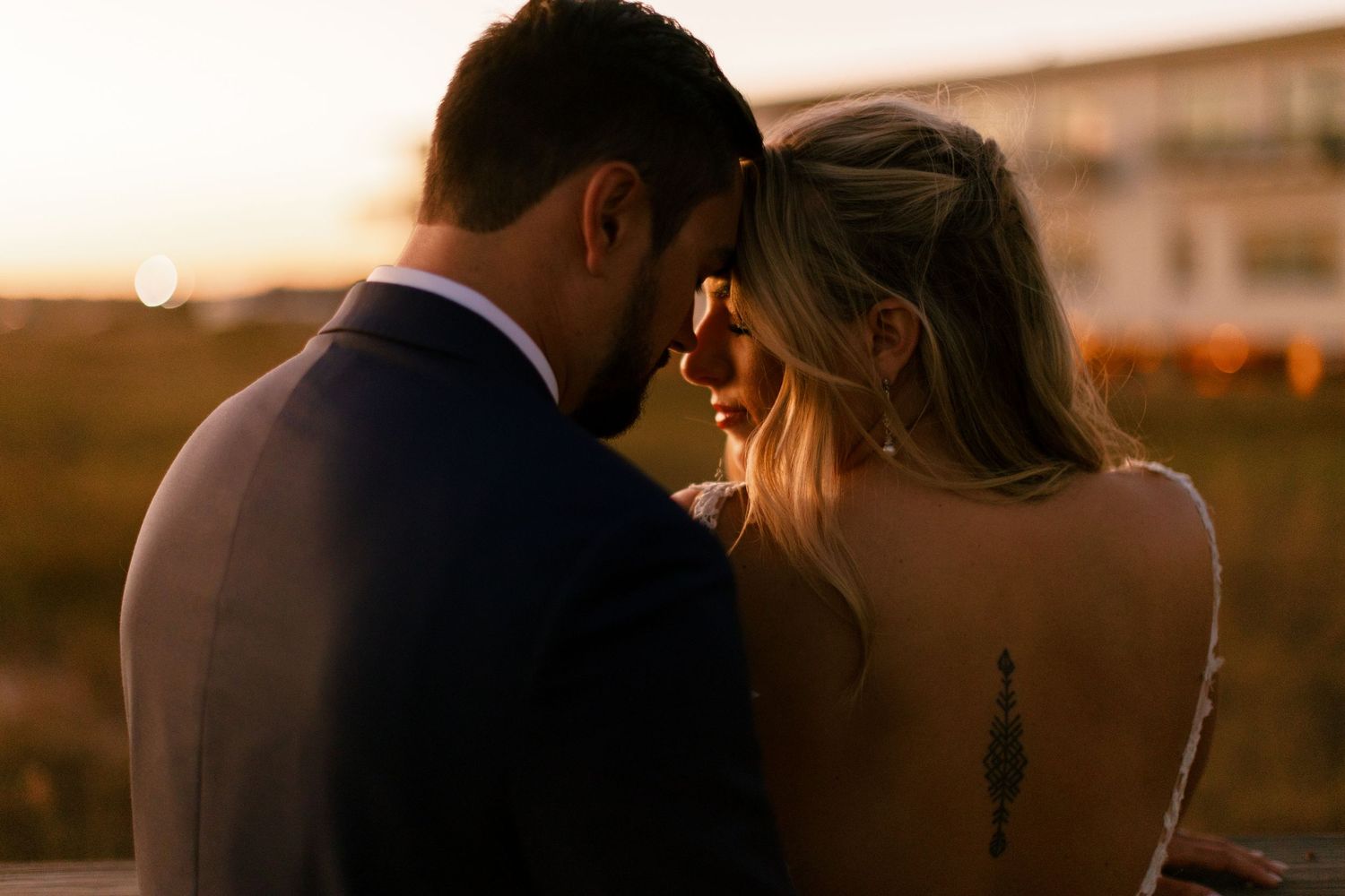Silhouetted wedding couple embraces during golden hour on the beach.