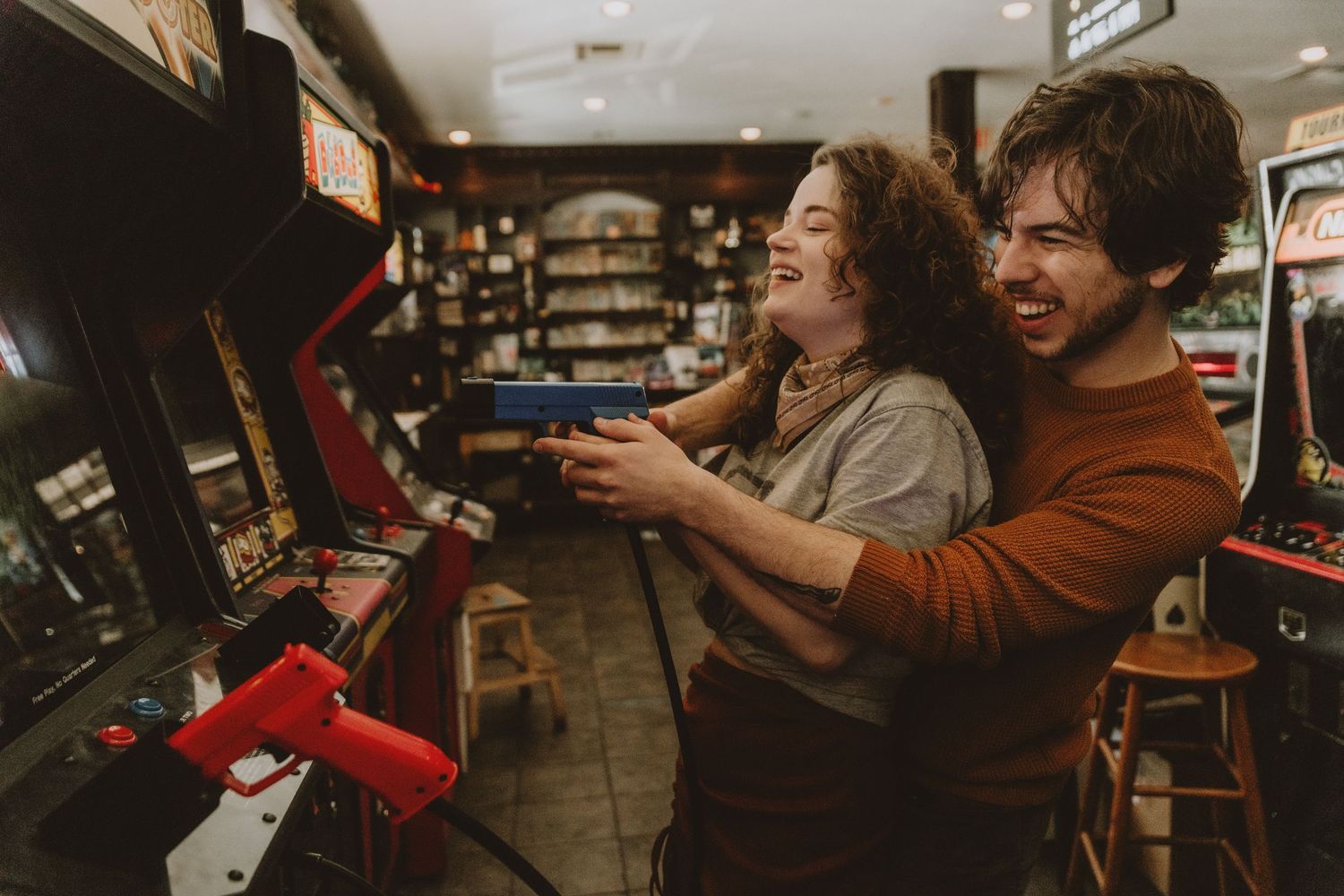Two people having fun playing vintage arcade games together in a classic arcade setting.