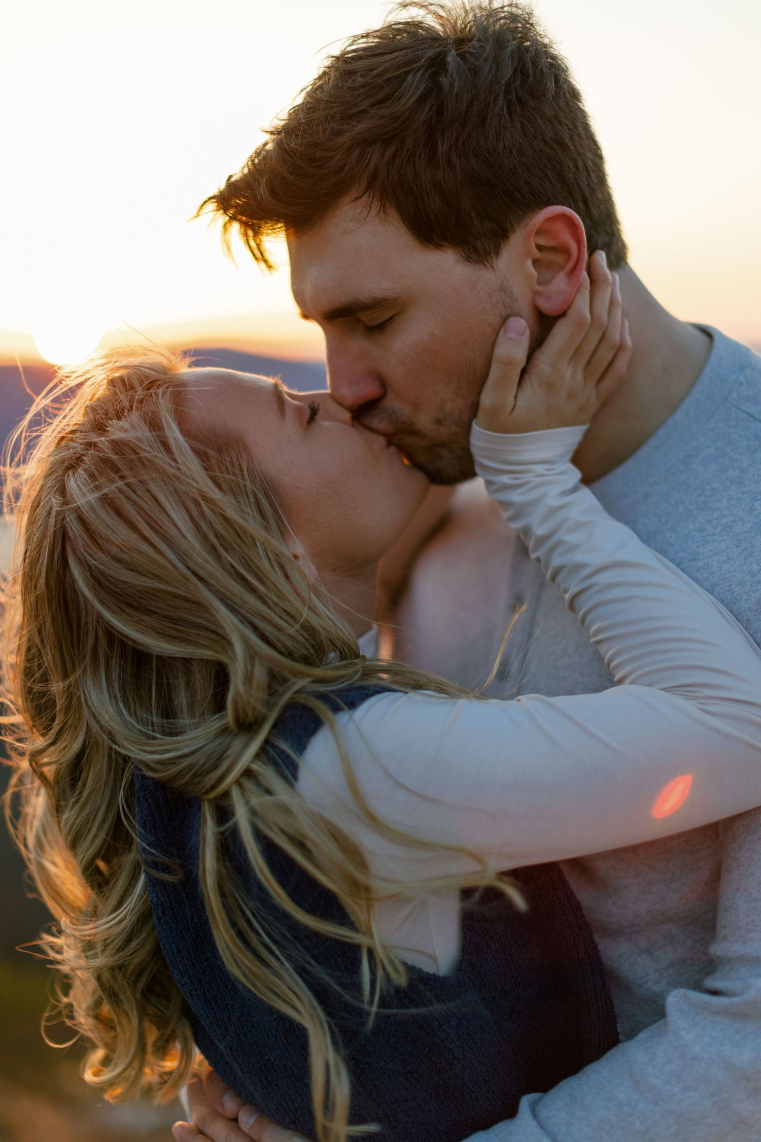 Romantic couple embracing and sharing intimate moments during sunset.