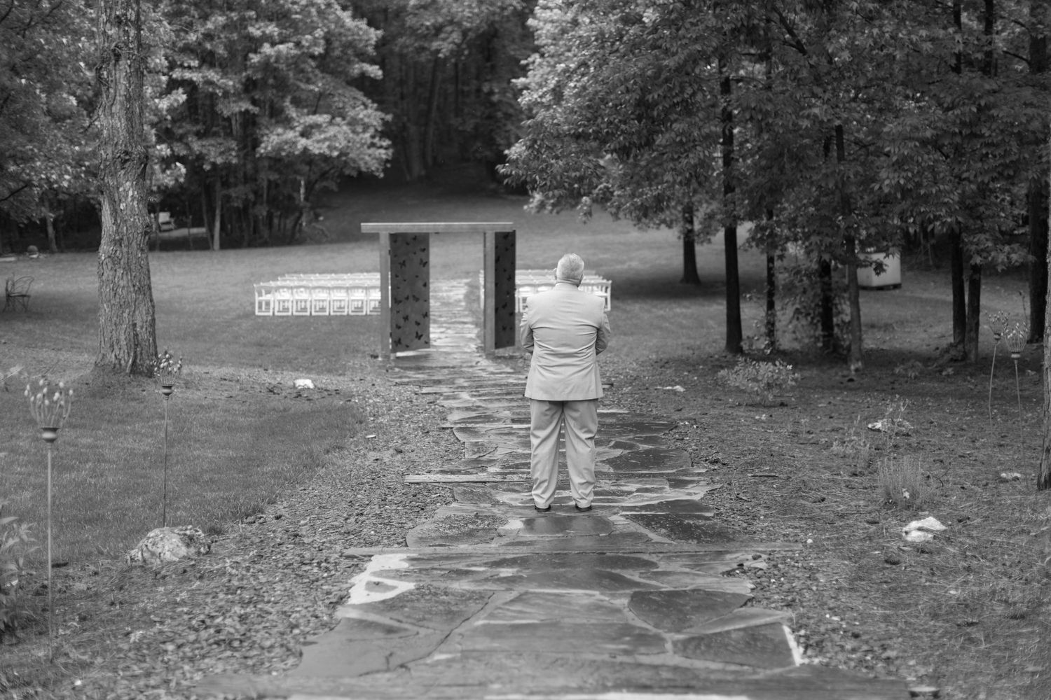 A figure stands on a stone pathway in a black and white outdoor scene.