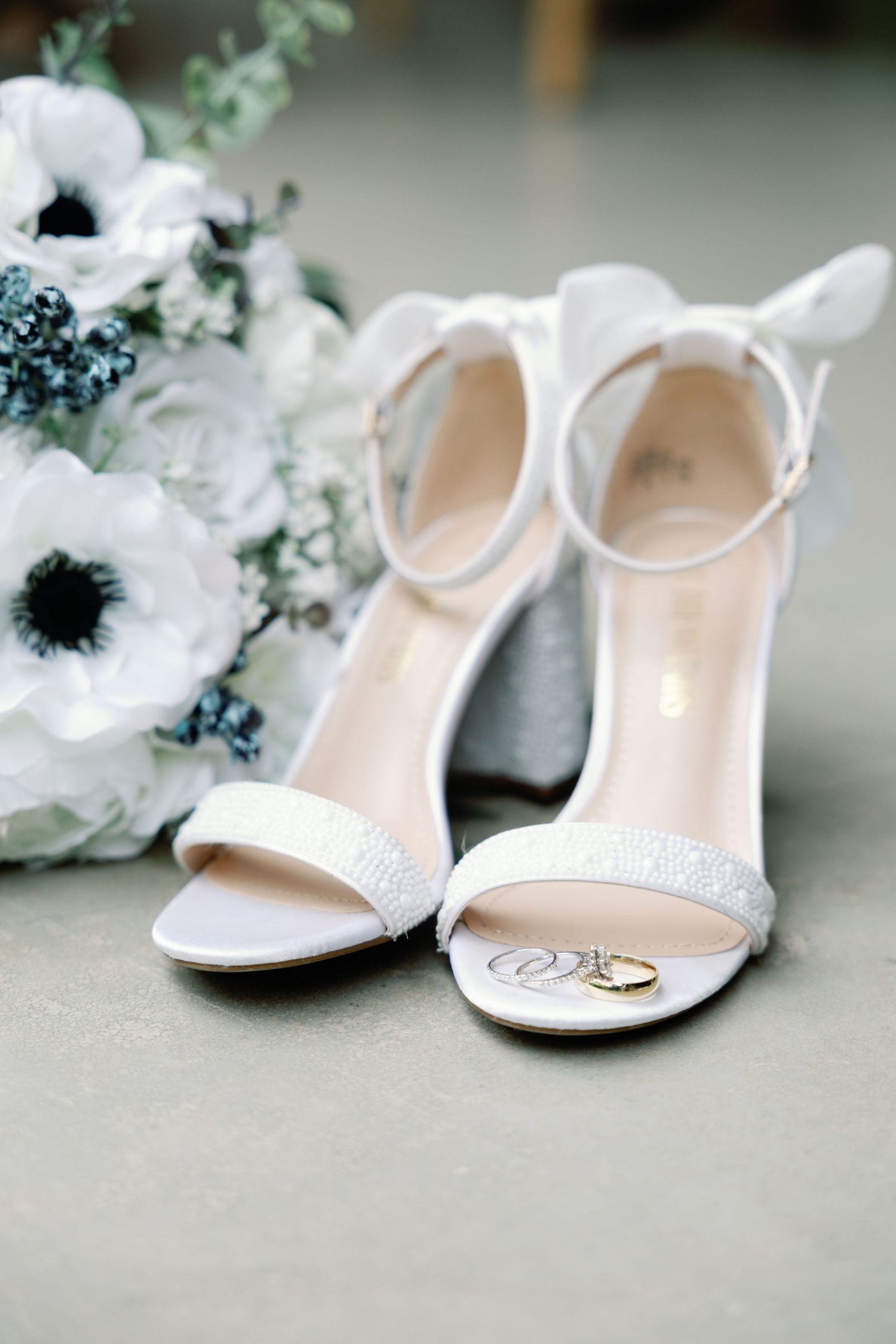 Elegant white bridal shoes with crystal details displayed with floral accents.