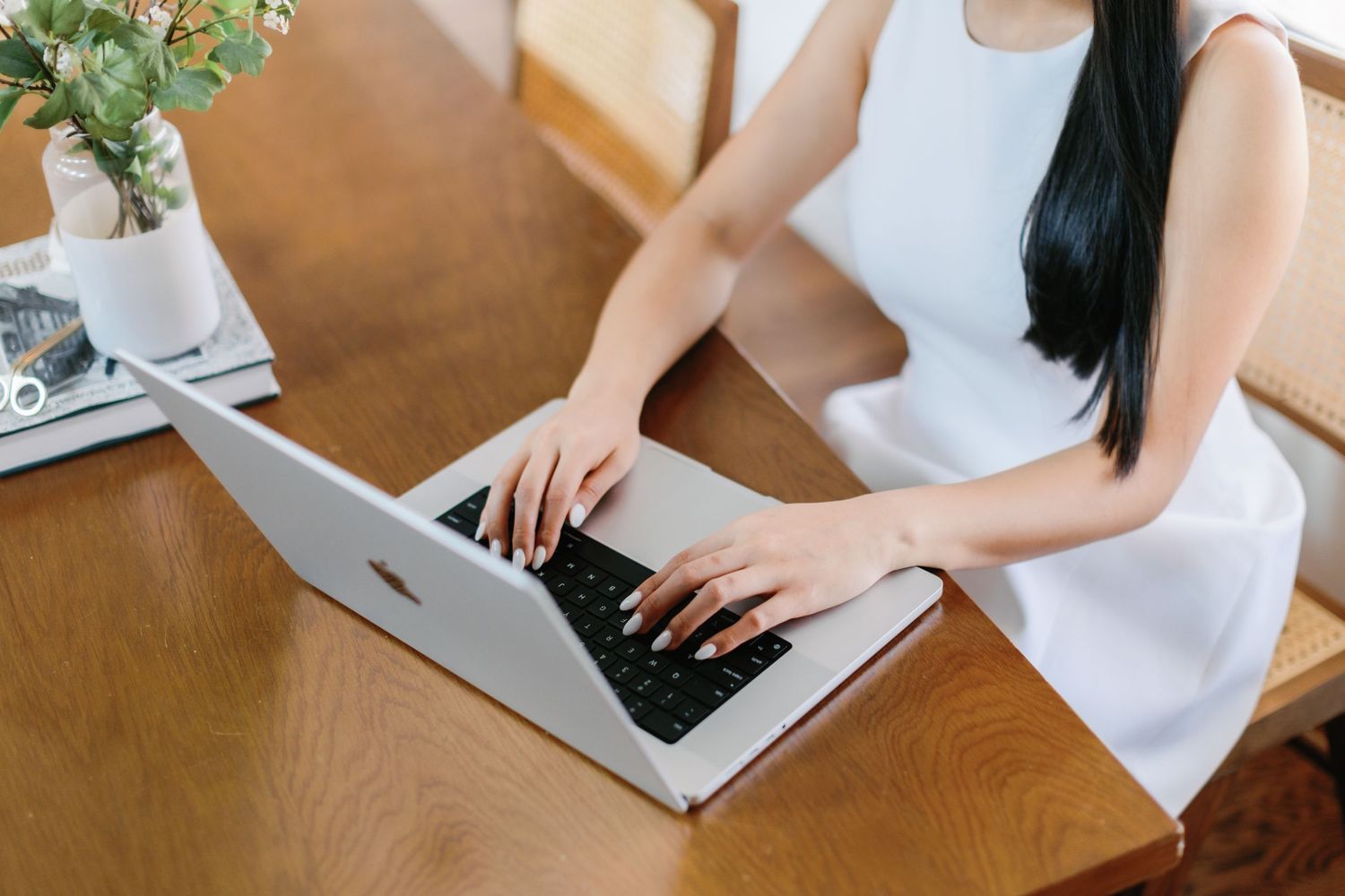 Overhead view of laptop and work materials on wooden surface with greenery.