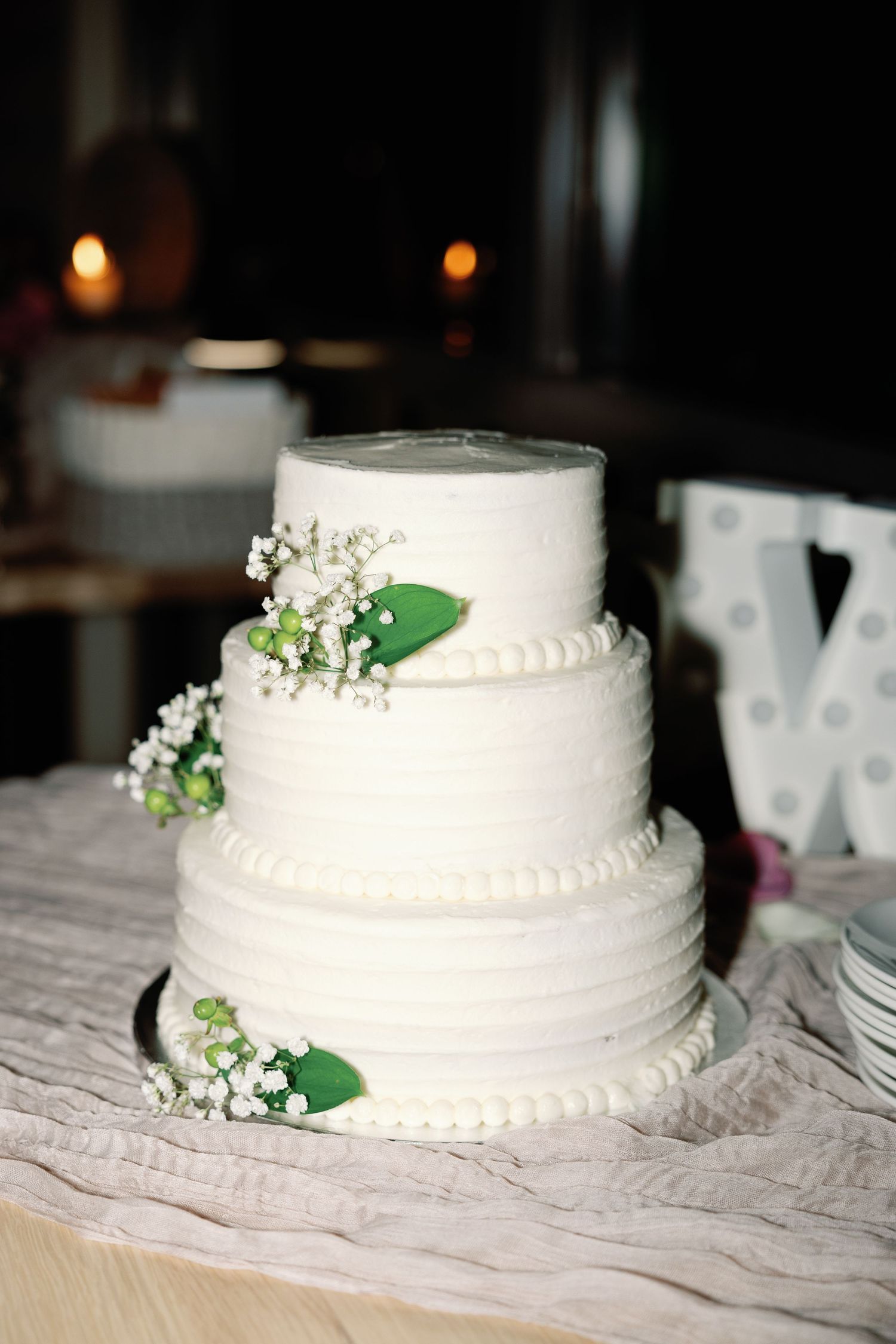 Classic white wedding cake decorated with small green leaves and flowers.