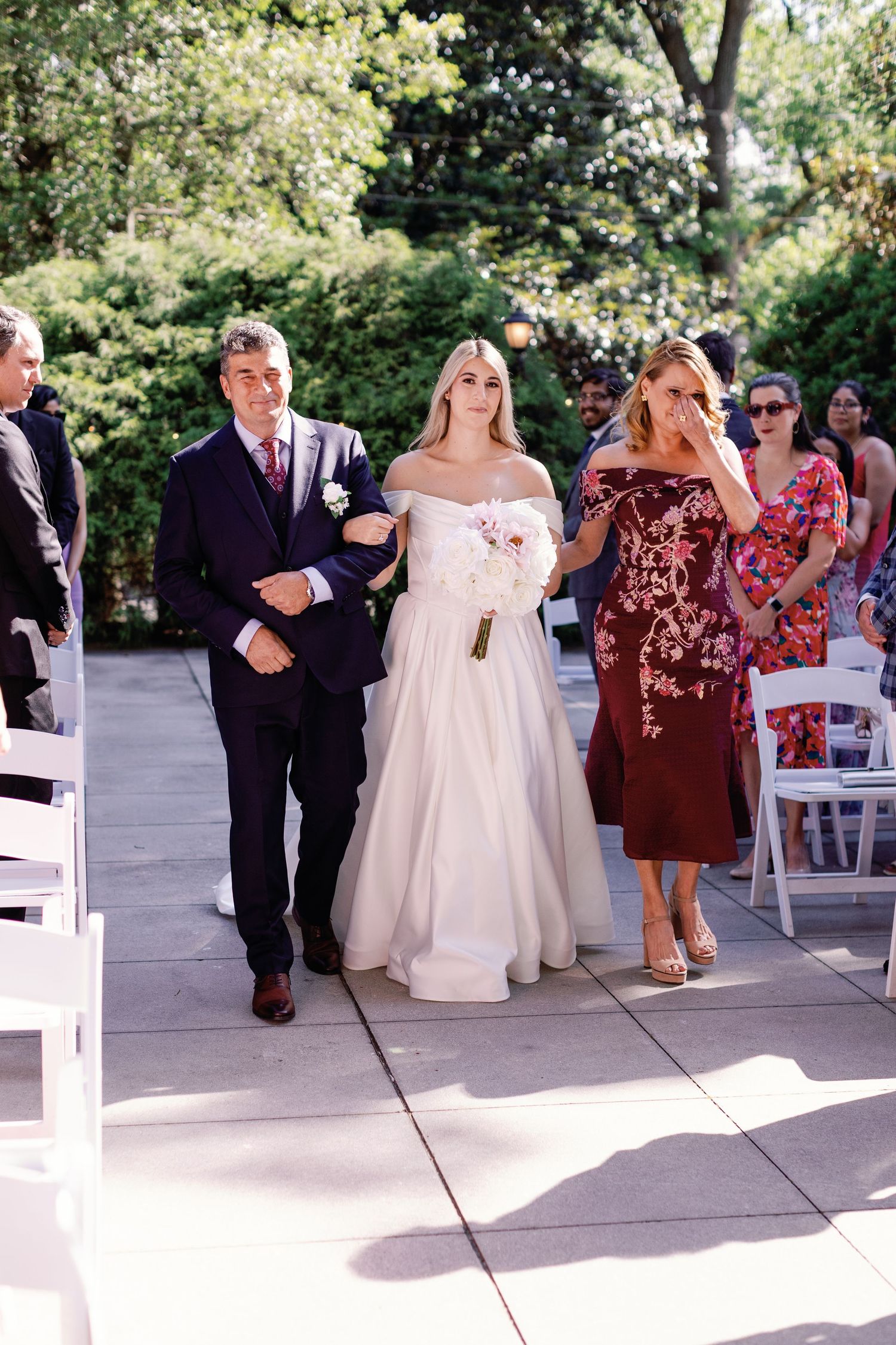 Wedding guests and bridal party gather on a sunny patio during the celebration.