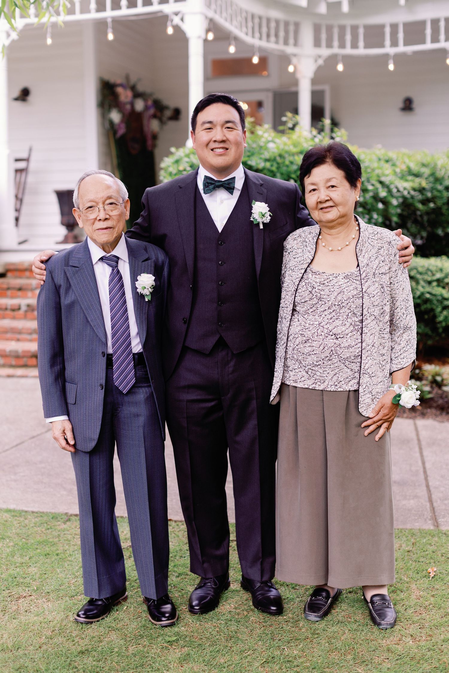 Wedding family portrait with formal attire in front of a colonial-style building.