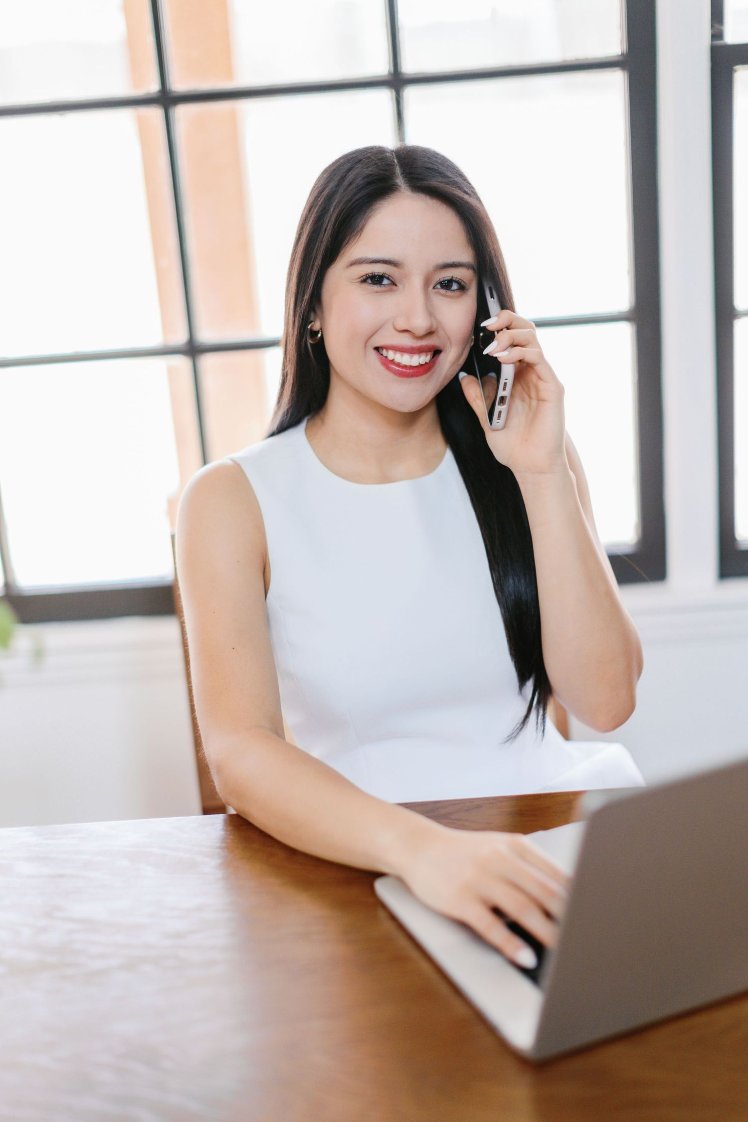 Person working on laptop at wooden table in bright modern office space.