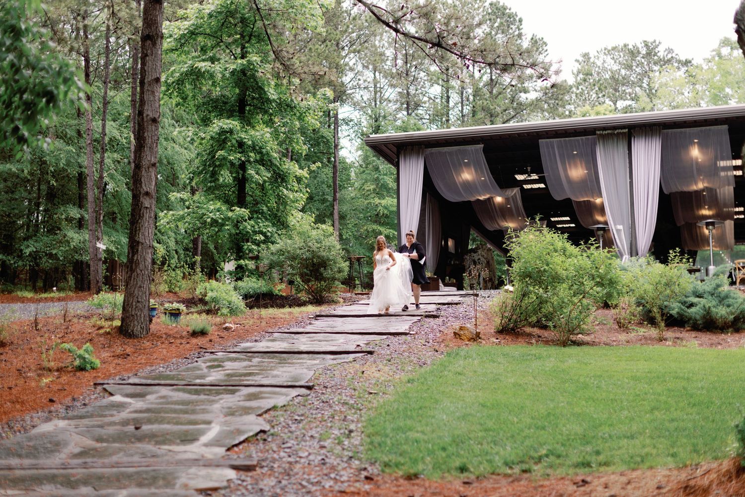 A lush outdoor garden venue with gravel paths and trees in natural lighting.
