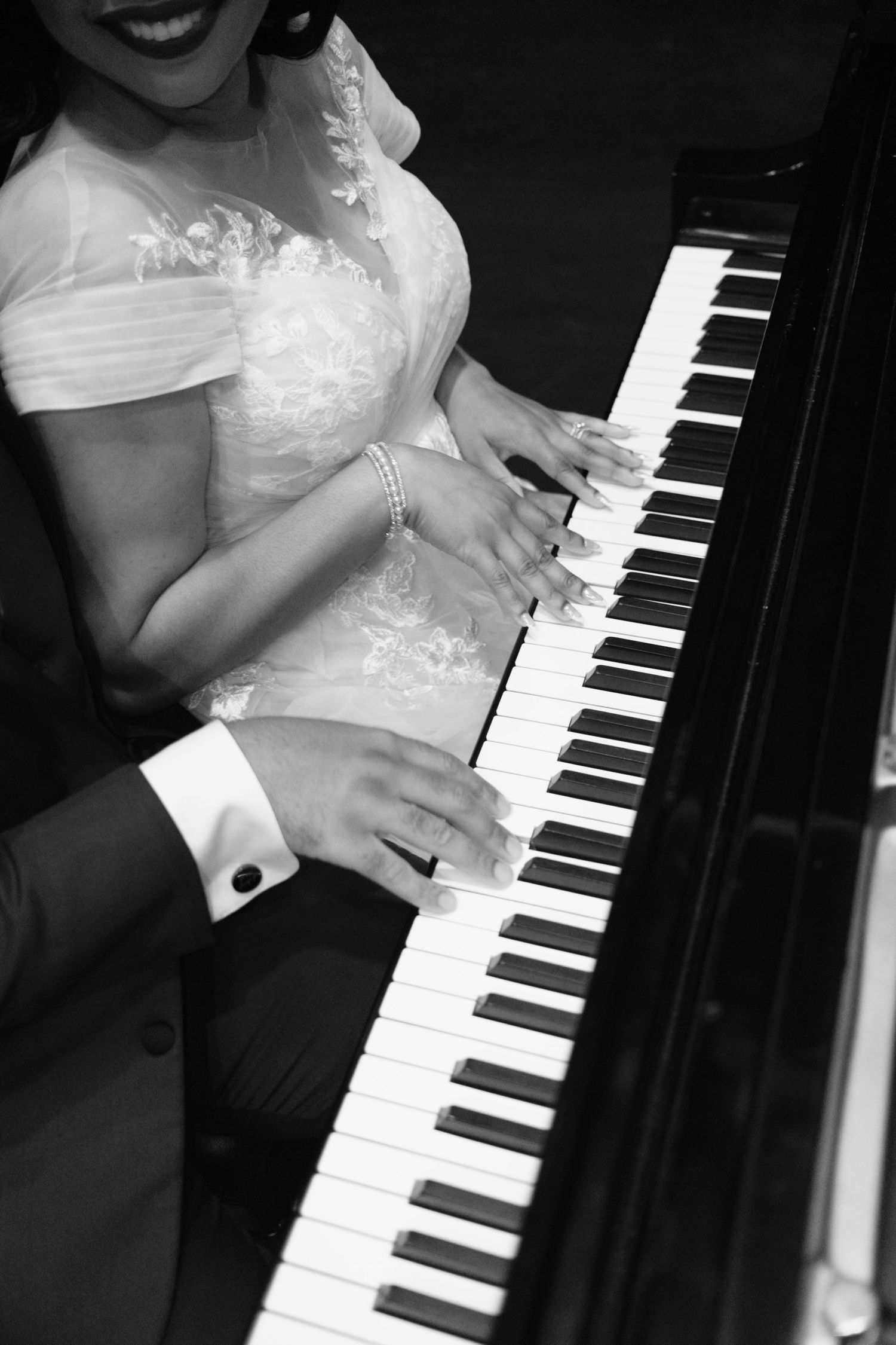 Close-up shots of hands playing piano keys in black and white, showing delicate finger movements.
