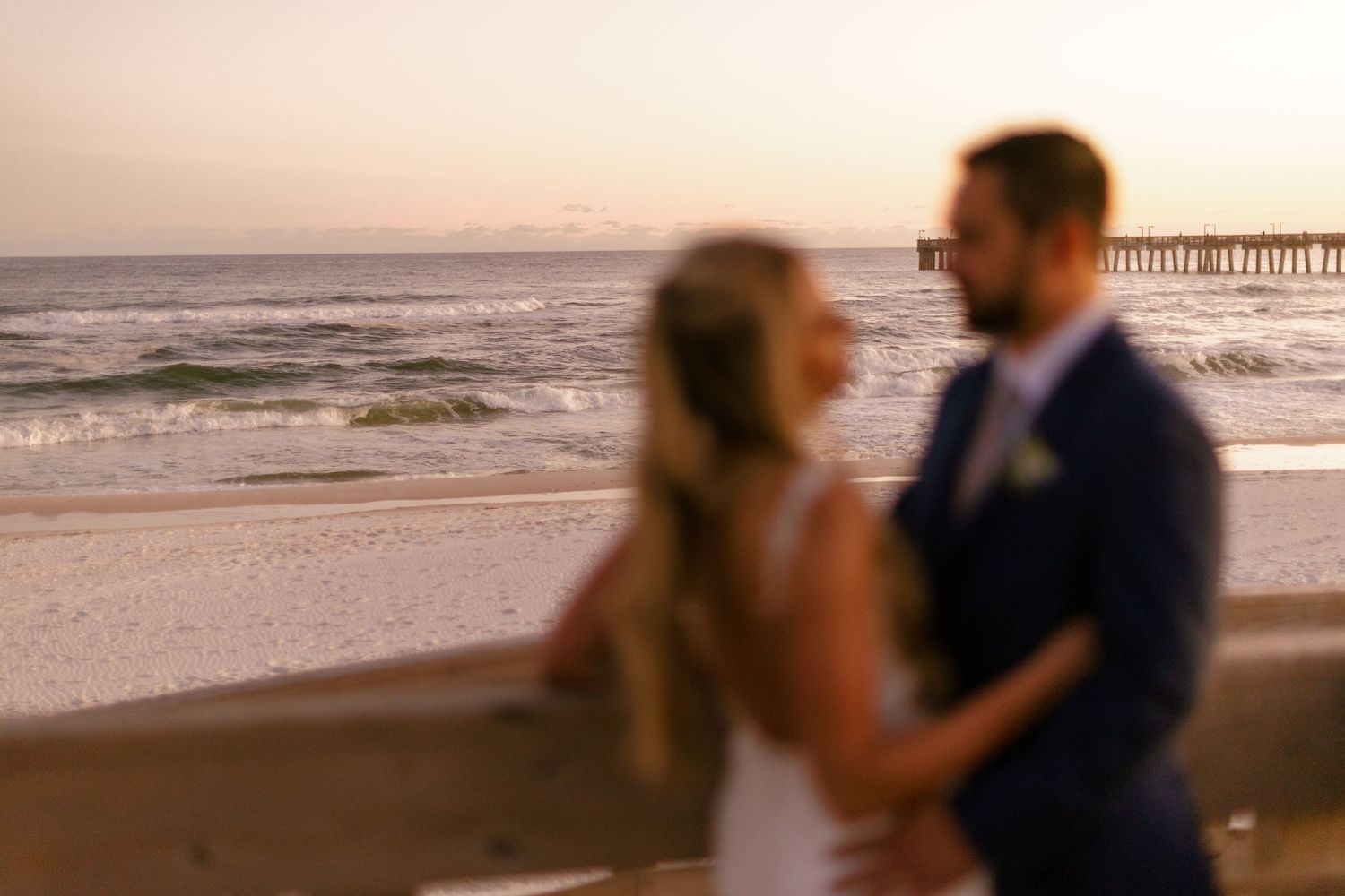 Romantic beach photoshoot at golden hour with waves crashing in background.