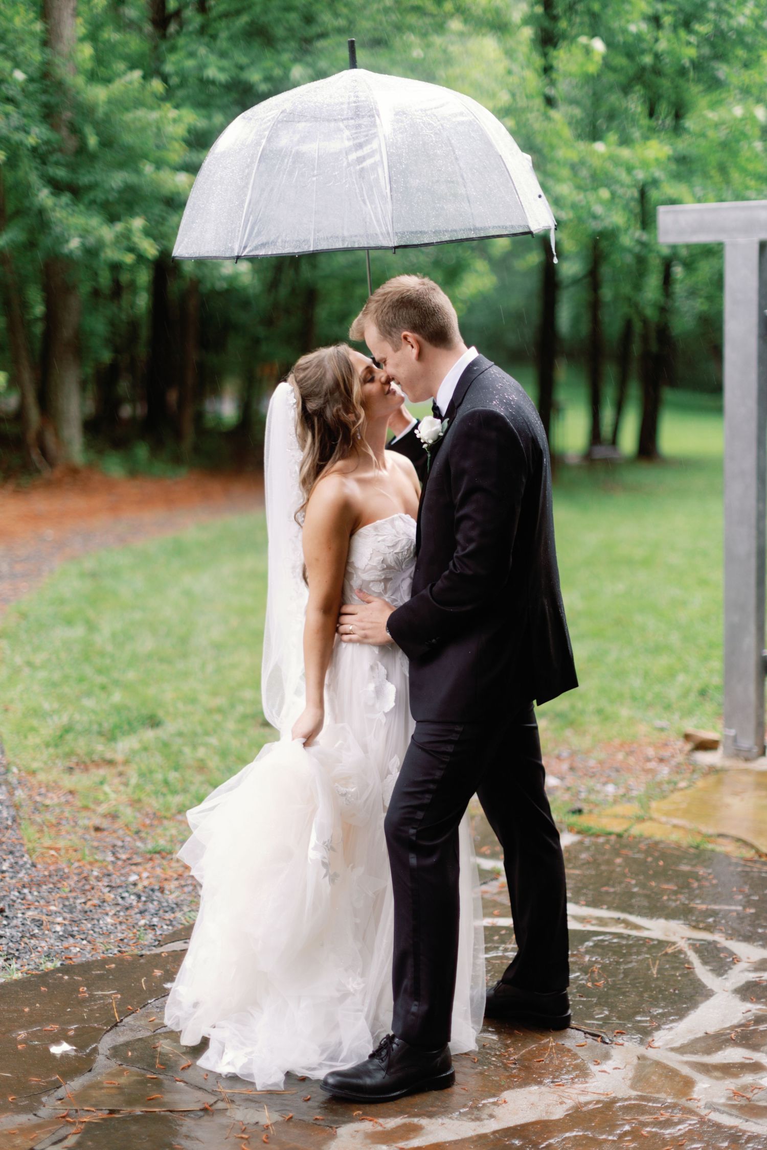 A couple shares a romantic moment under a clear umbrella in the rain.