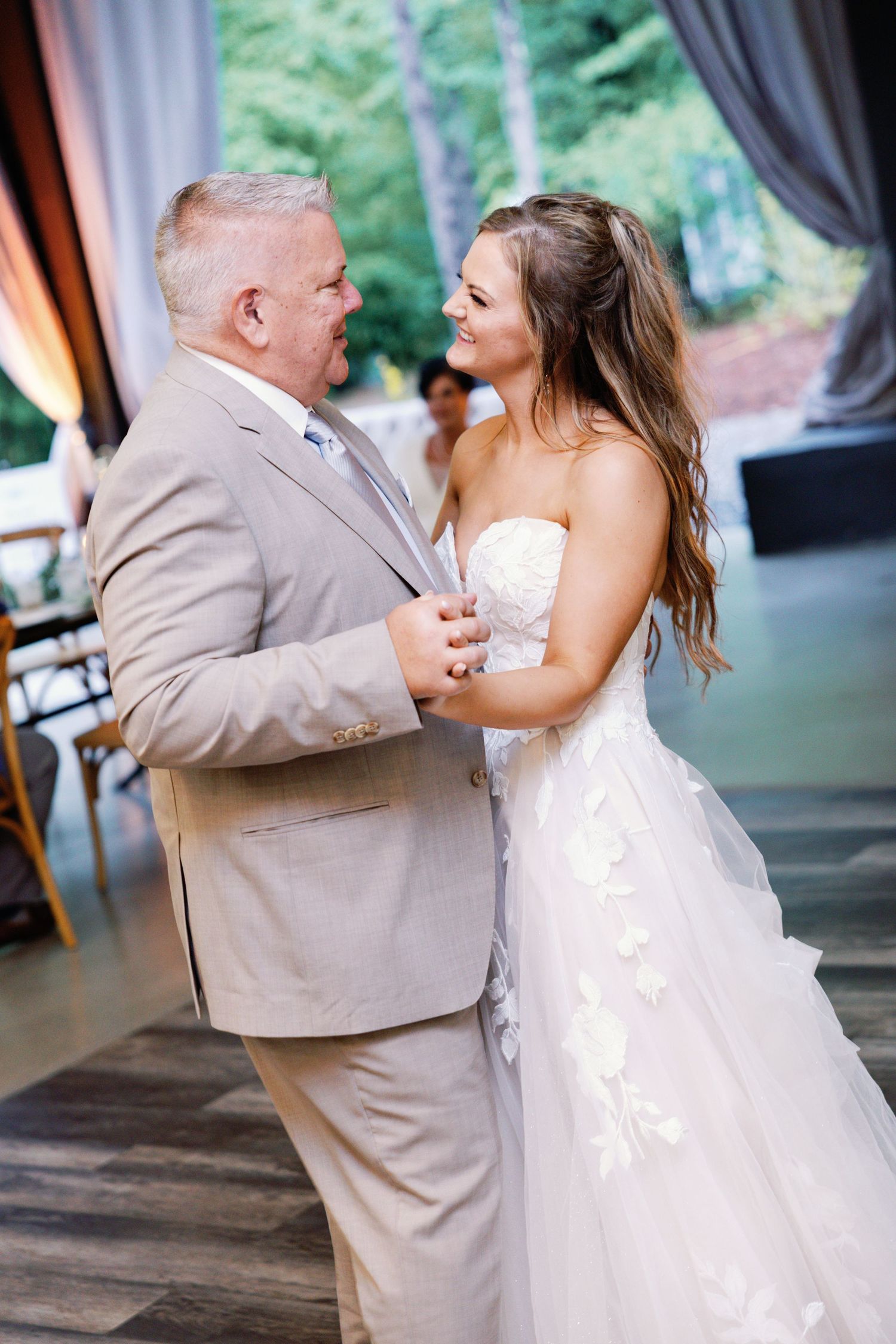 Wedding dance between bride in white gown and guest in tan suit during reception.
