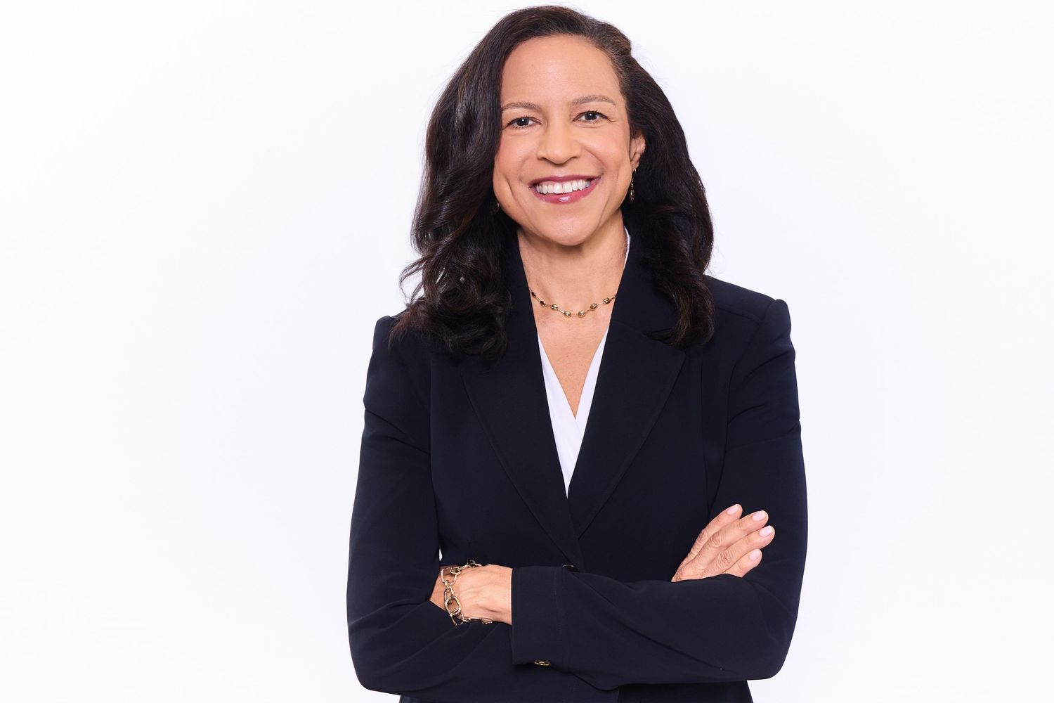 Atlanta headshot of business professional indark blazer and white blouse stands with arms crossed and a warm smile against white background