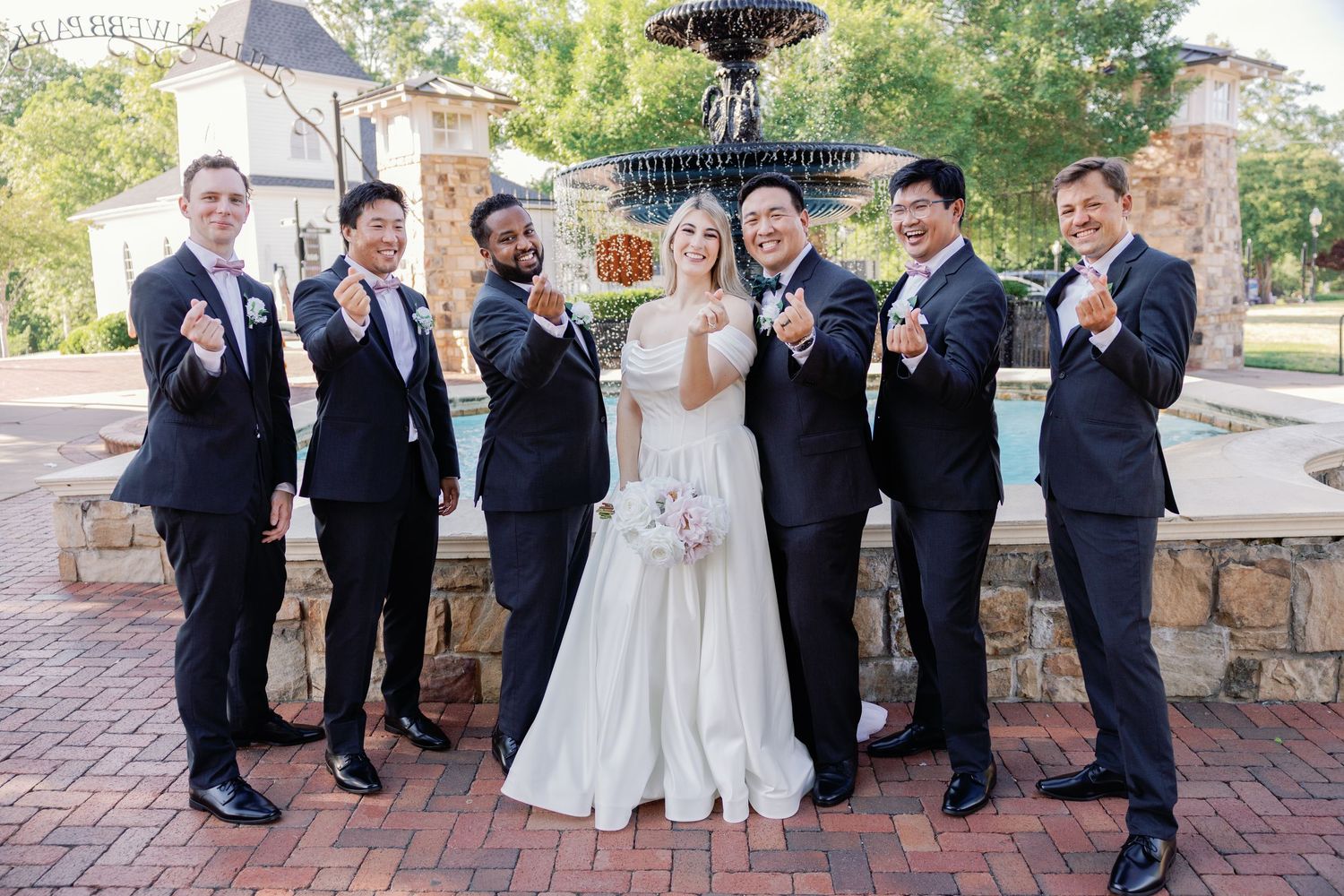 Wedding party members in burgundy and black attire pose playfully for group photos.