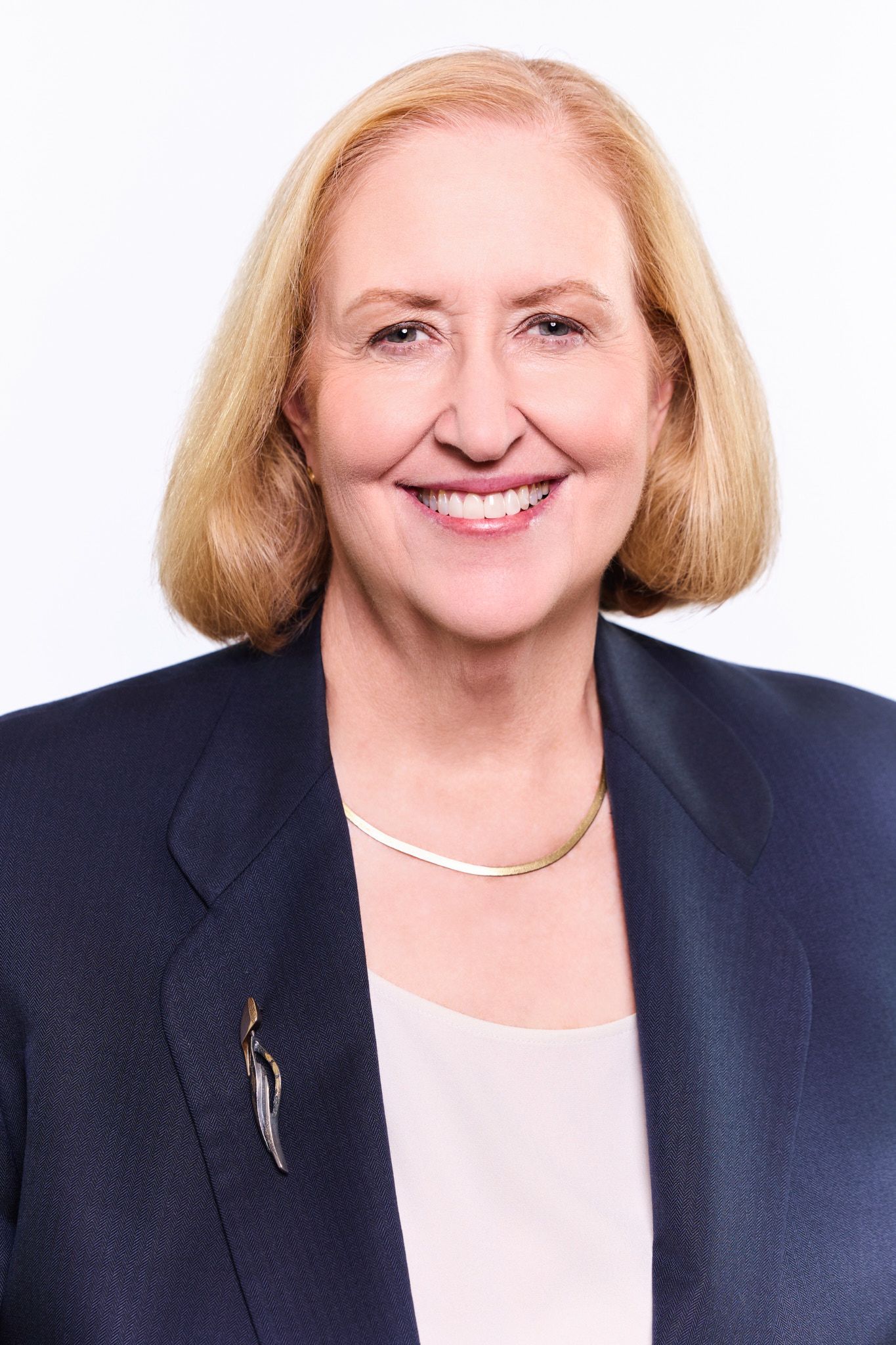 Professional headshot series showing a person in a navy blazer and light top smiling warmly against white background.