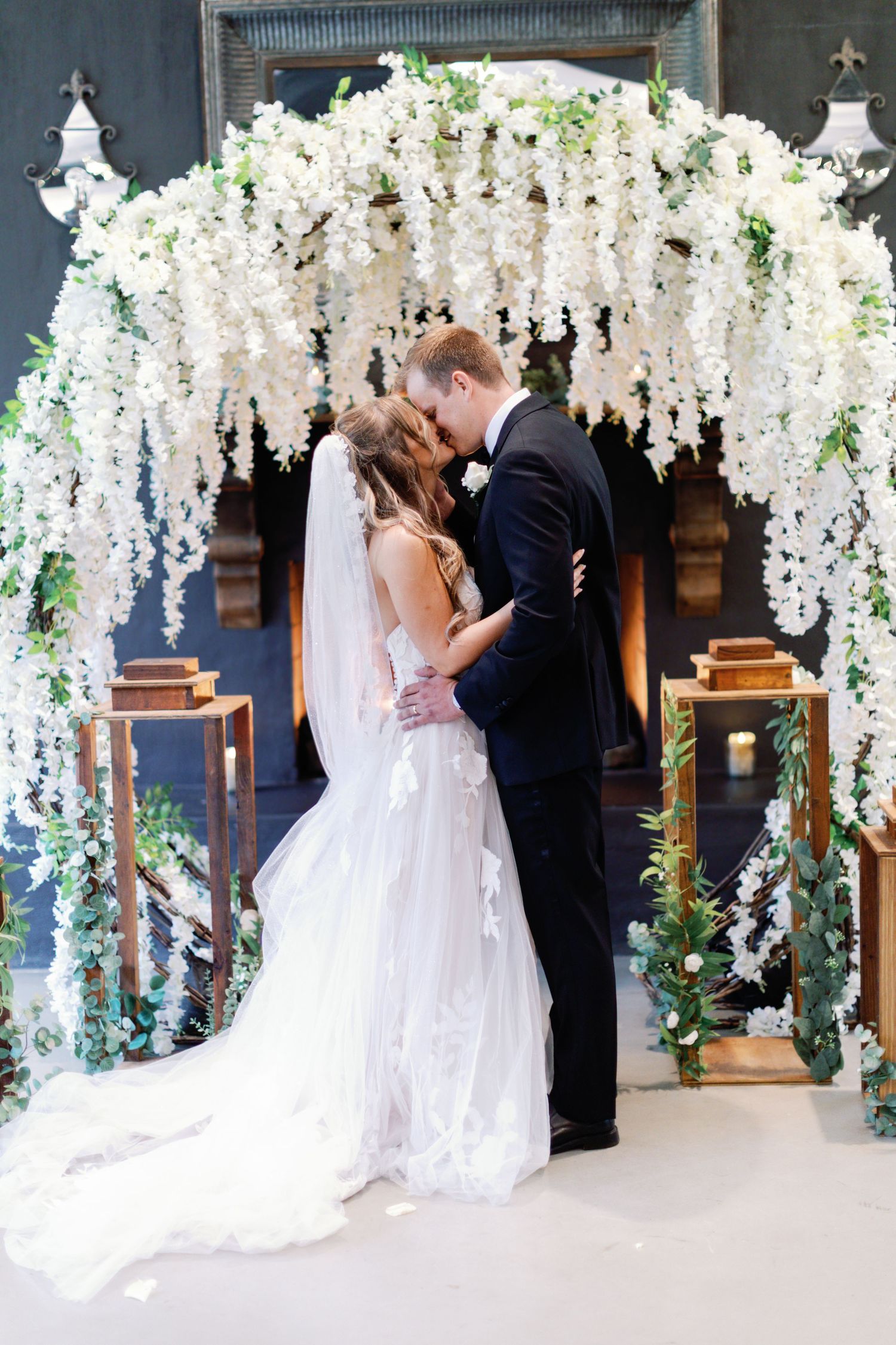 A wedding ceremony sequence under stunning white wisteria floral arches with elegant decor.