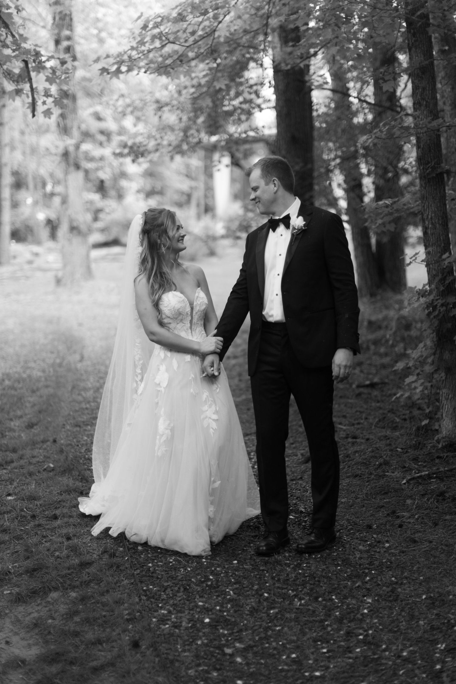 Black and white outdoor wedding photos showing couple walking through wooded area.
