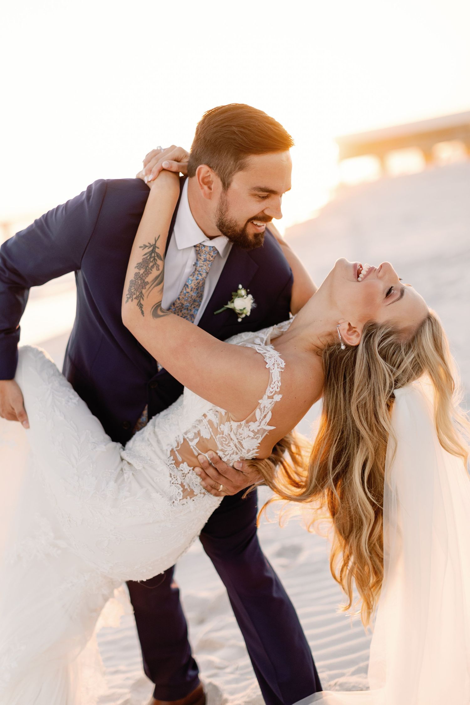 A couple performs a dramatic dancing dip pose during their beach wedding photoshoot.