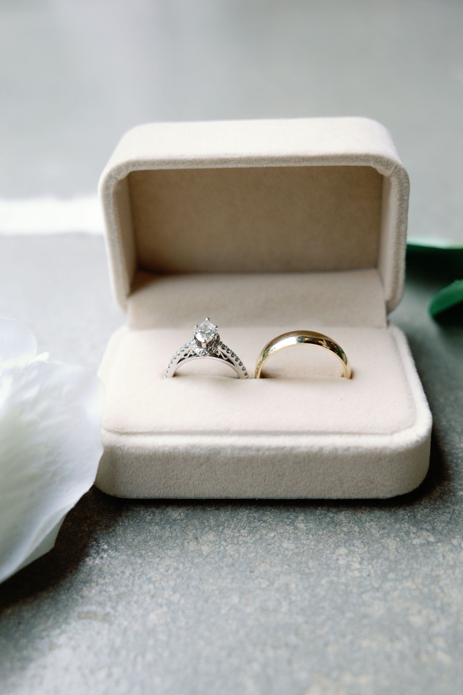 Wedding rings nestled in white velvet ring boxes on a shimmering surface.