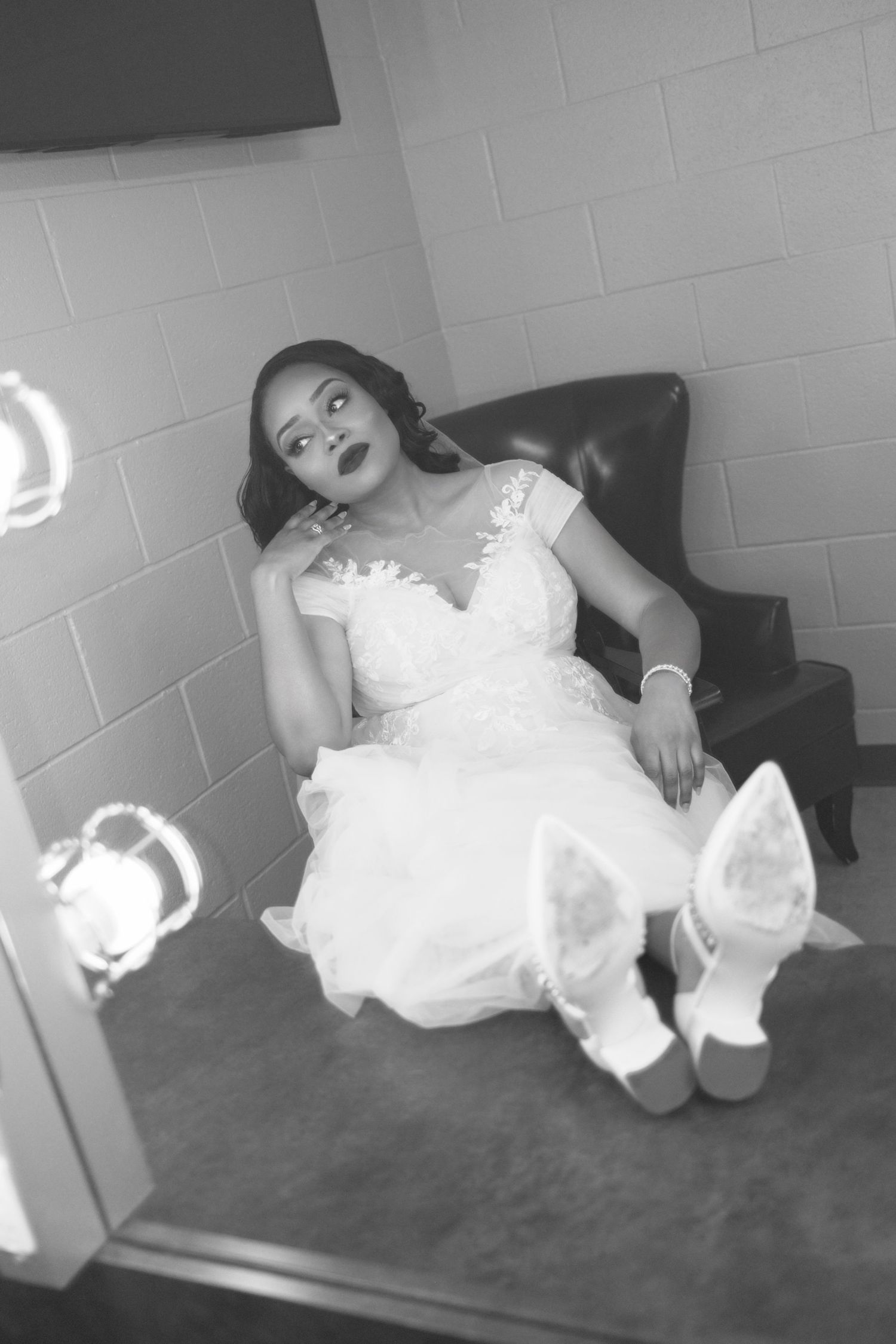 Bride in white dress poses playfully on the floor during wedding photoshoot.