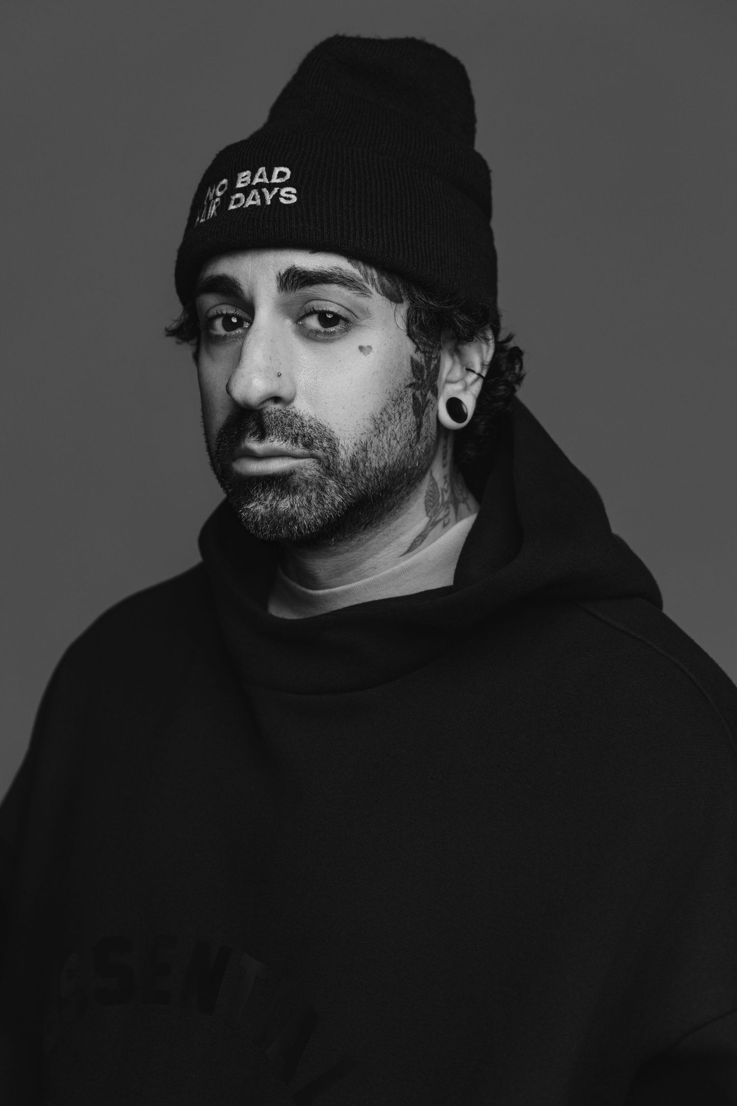 Black and white portrait series showing person in dark hoodie and beanie against gray background.
