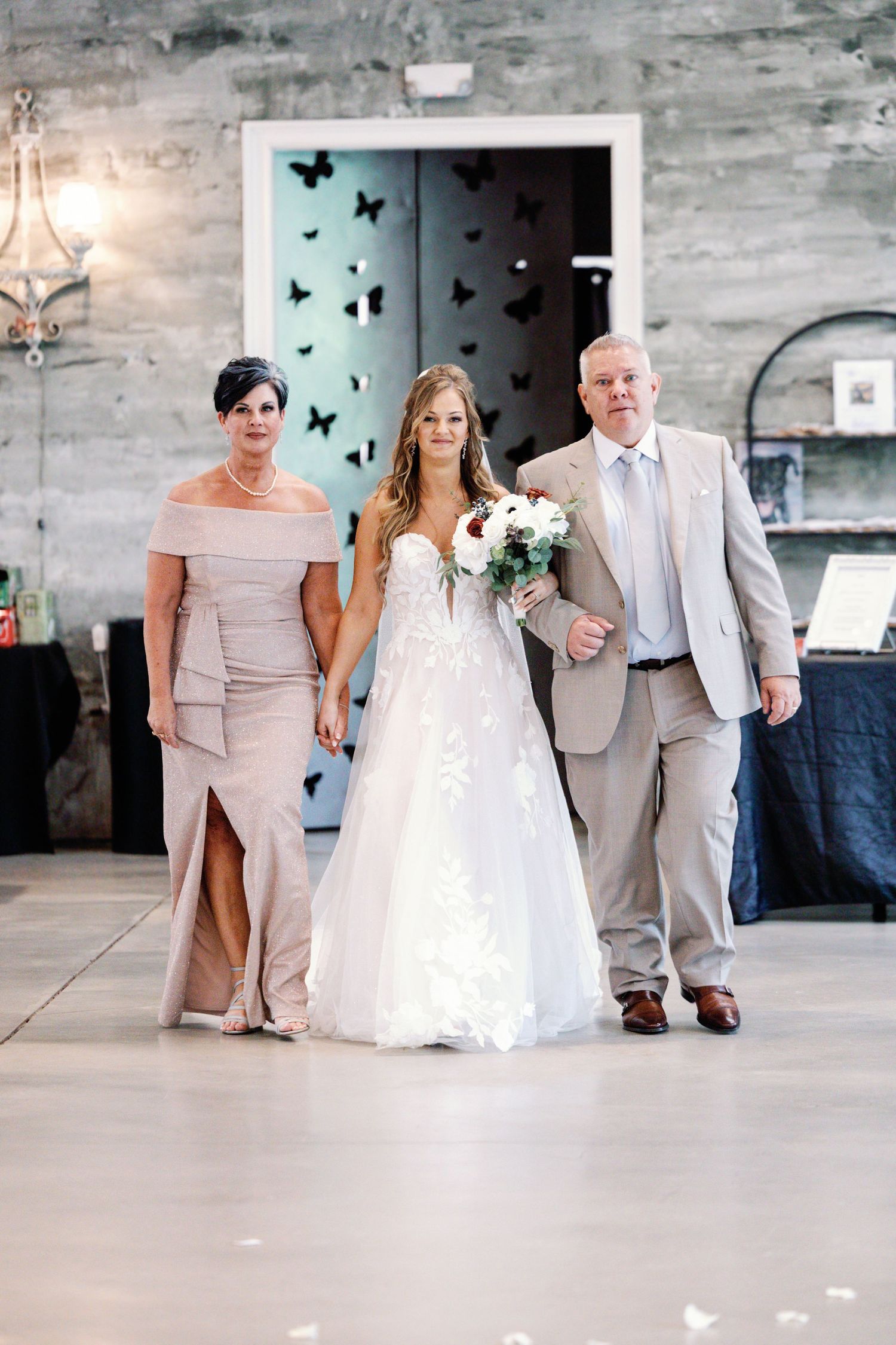 Wedding party walking in modern venue with decorative butterflies on wall.