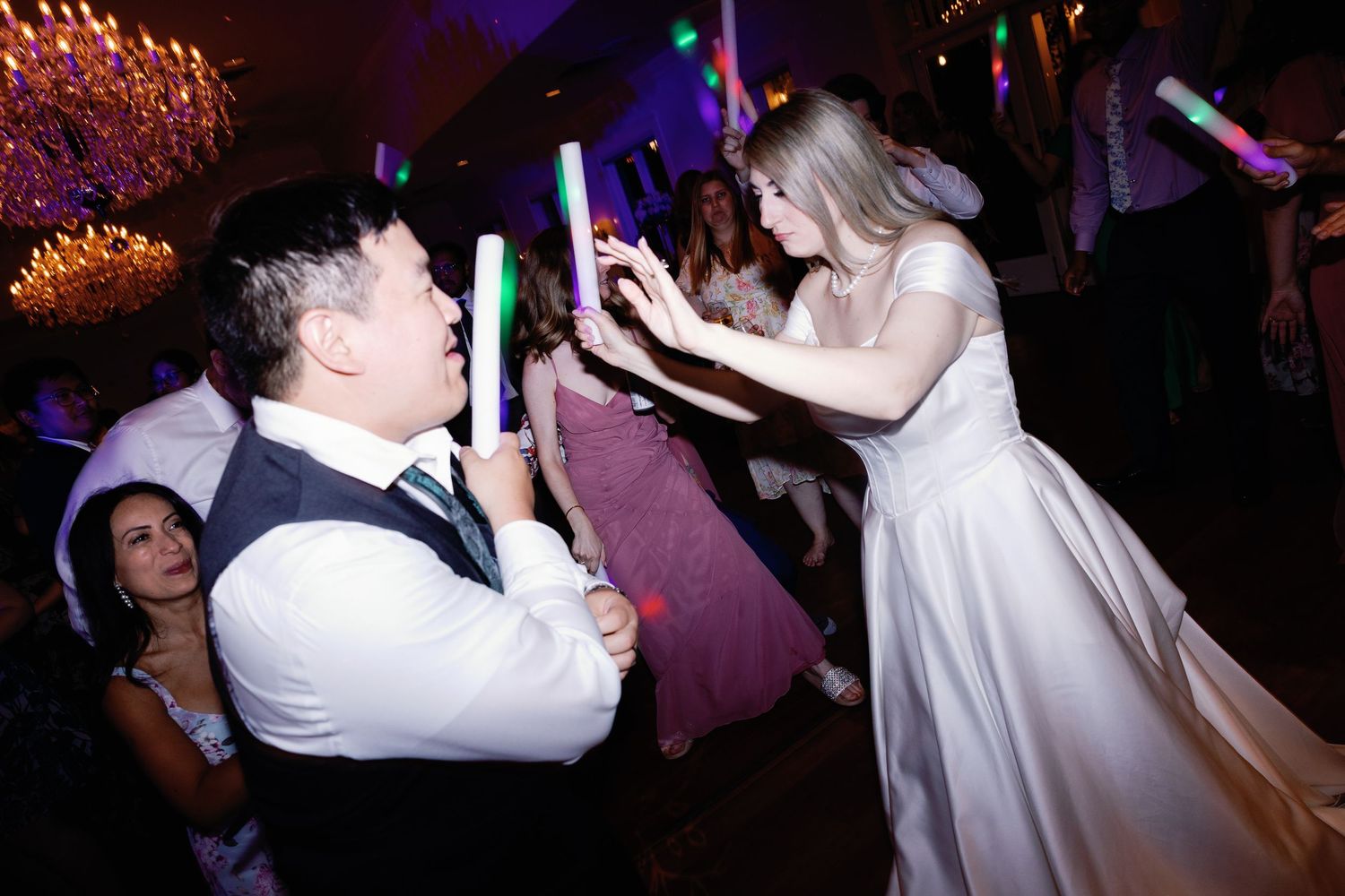 Couples dancing under colorful lights at an evening wedding reception.