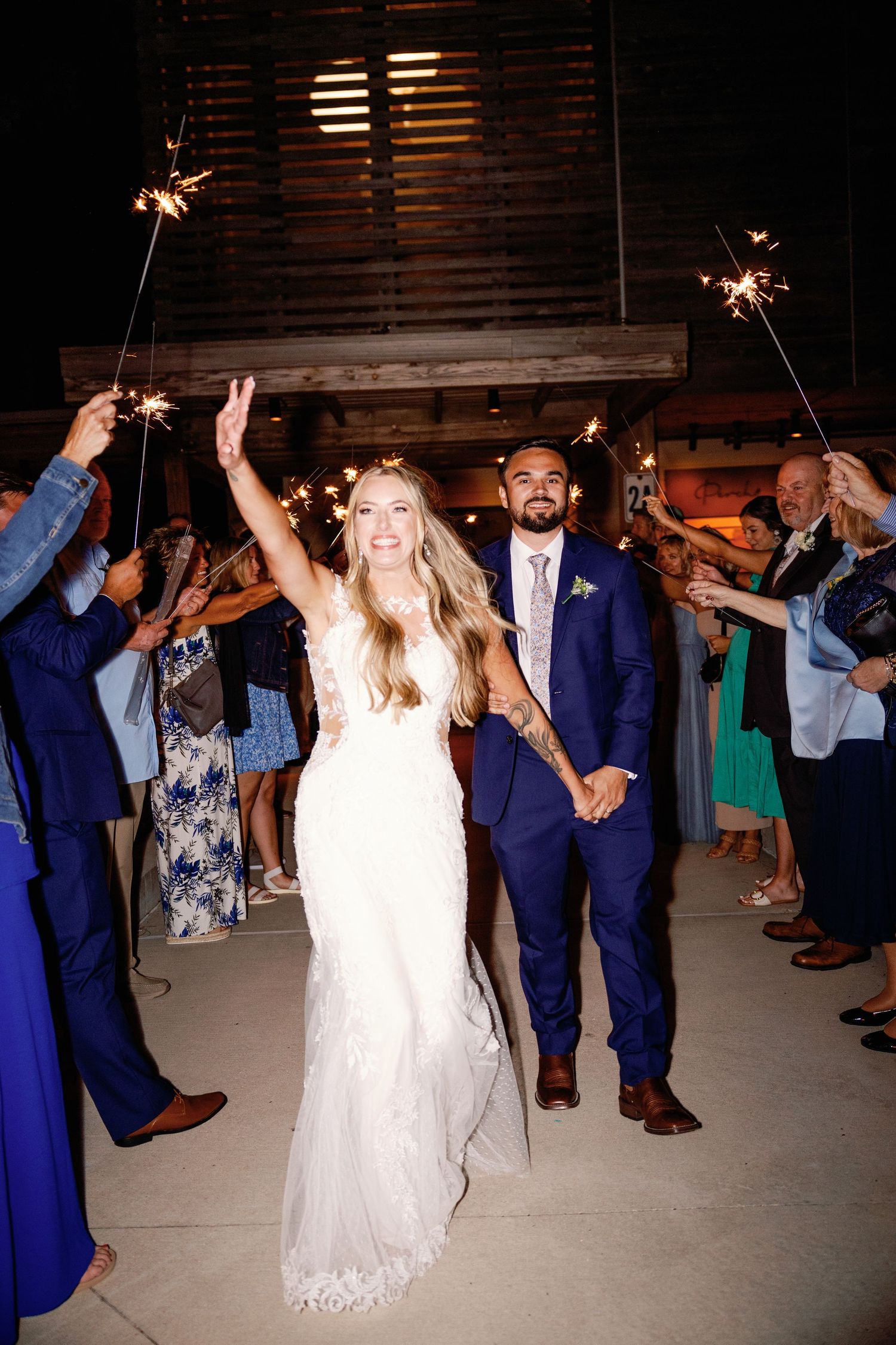 Wedding party dancing under sparklers during an evening celebration.