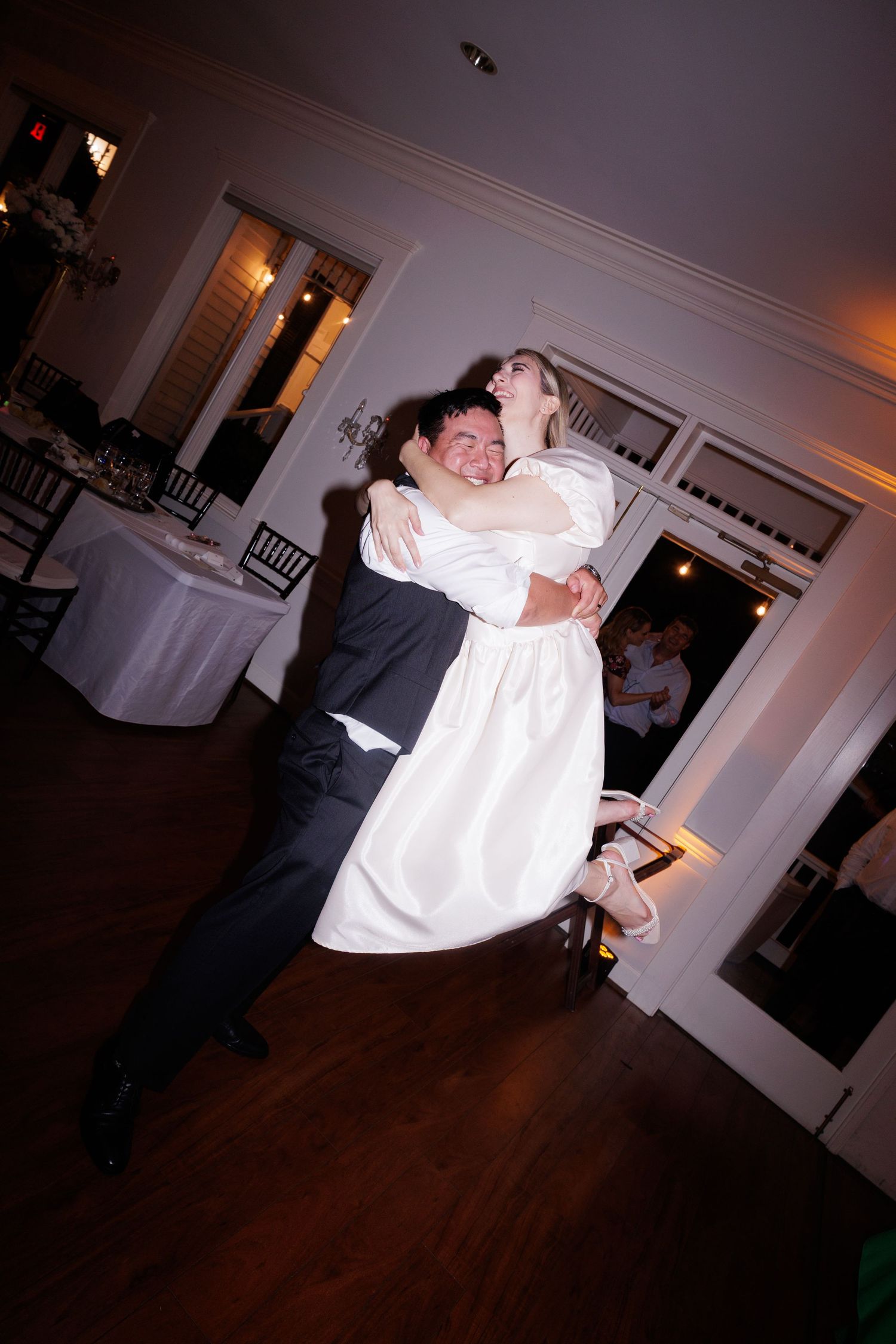 Couple shares an intimate dance moment on a hardwood floor during their wedding reception.