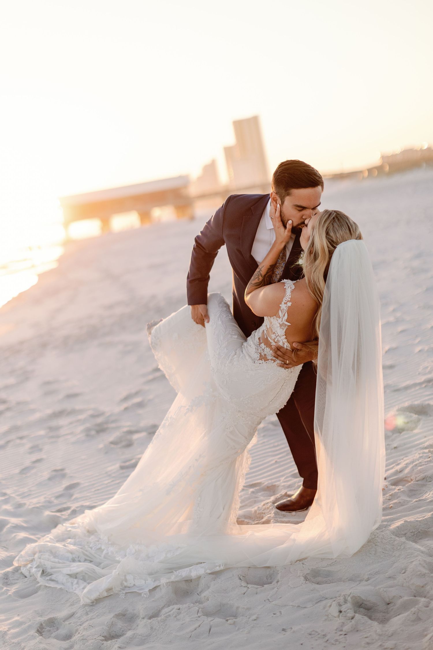Romantic beach sunset photos of couple in wedding attire on white sand.