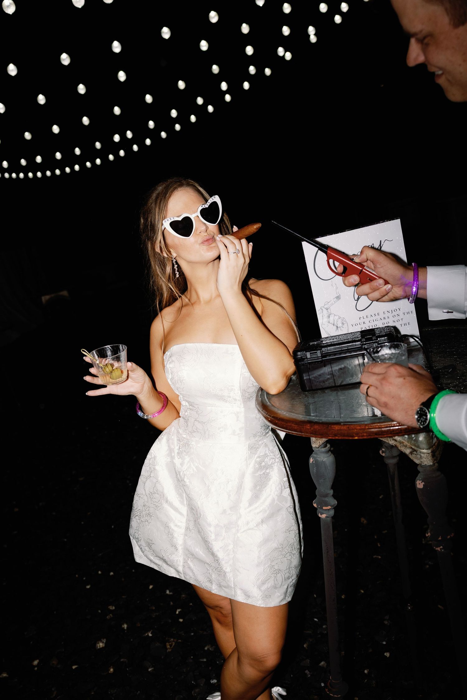 Wedding reception celebration with dancing in a dark room with string lights overhead.