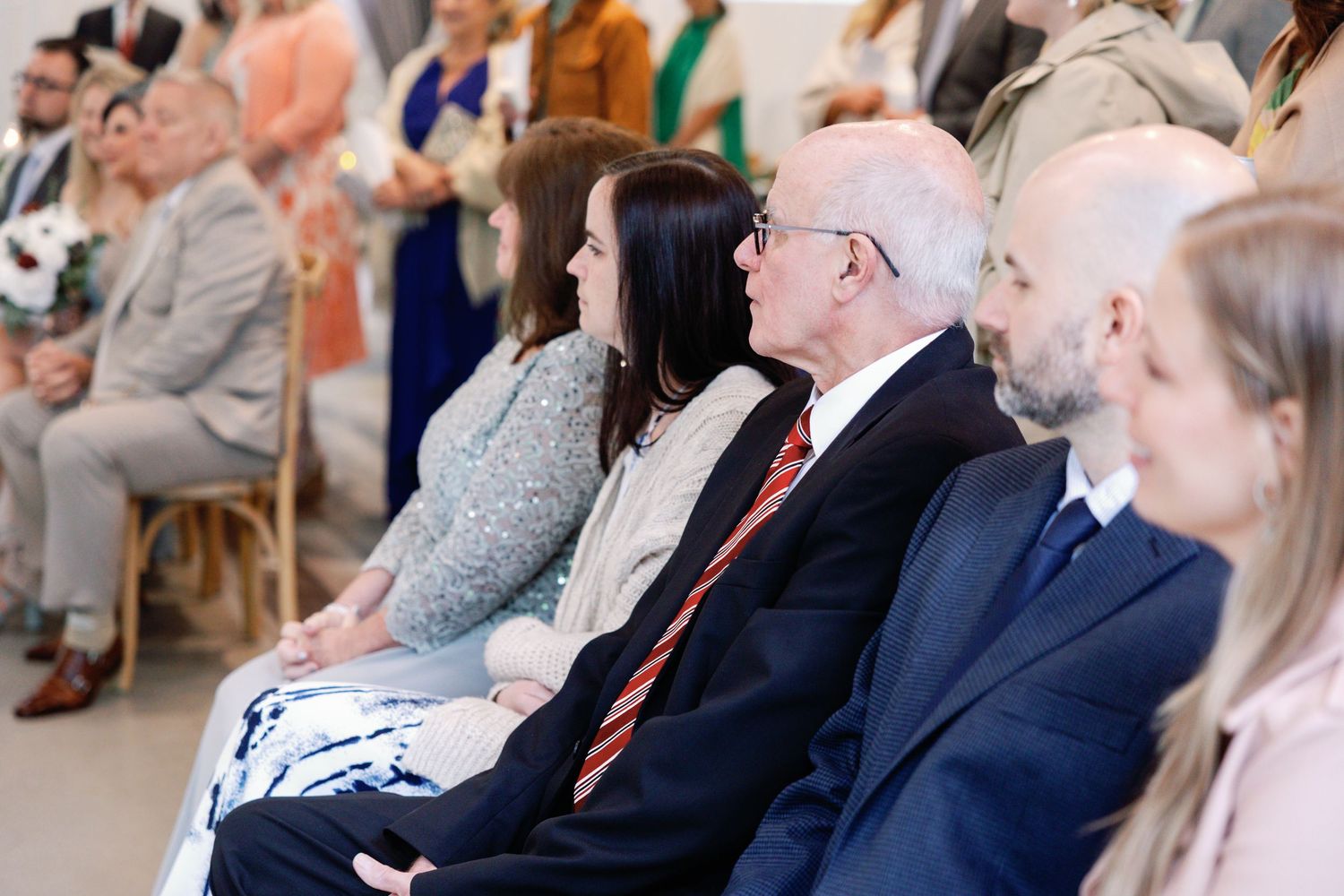 Wedding guests seated in rows watching the ceremony with attentive expressions.