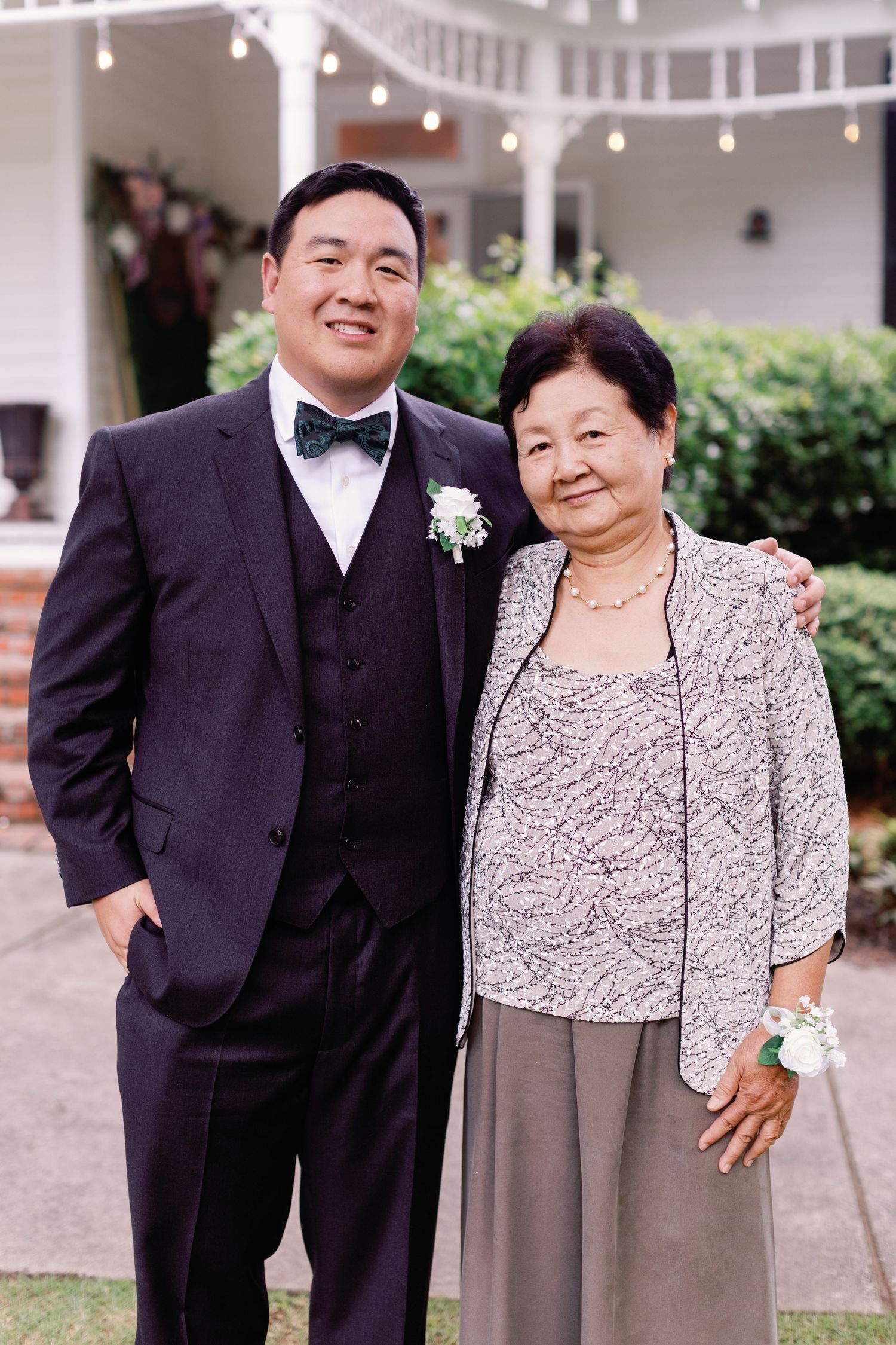 Family members in formal wear pose together at an outdoor wedding venue.