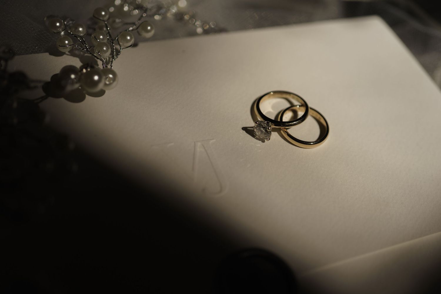 Flatlay of wedding rings and invitations—curated for a luxury destination celebration.