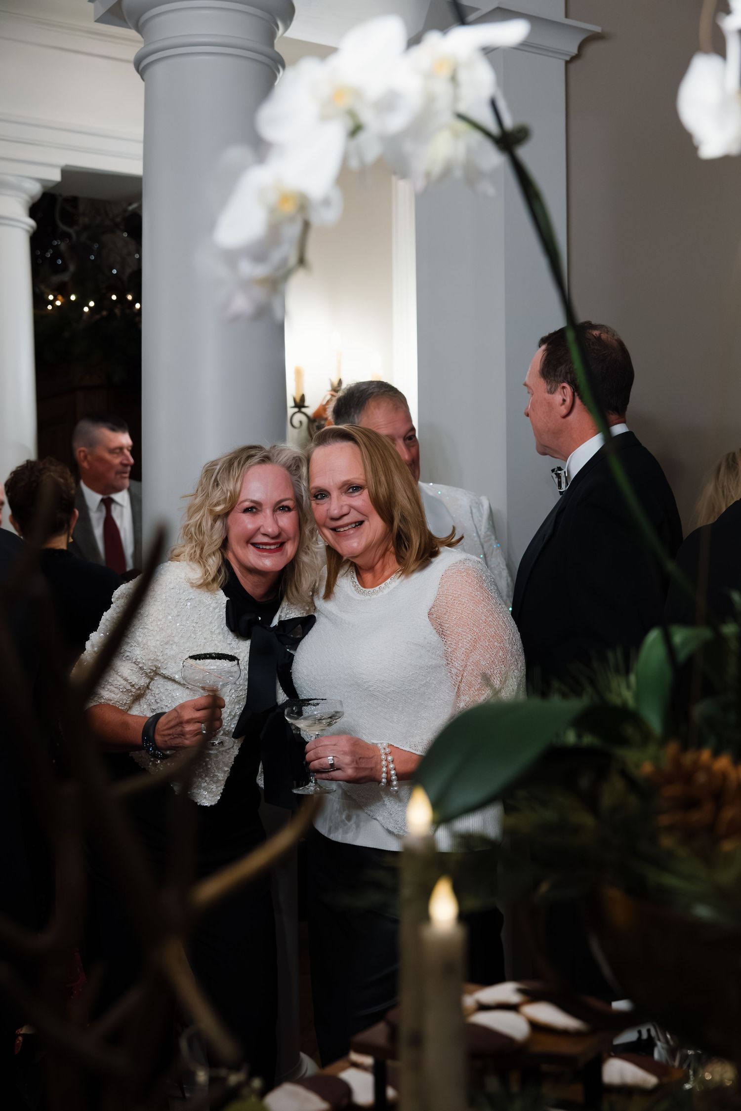 Elegant party gathering with white orchids and columns in the background.