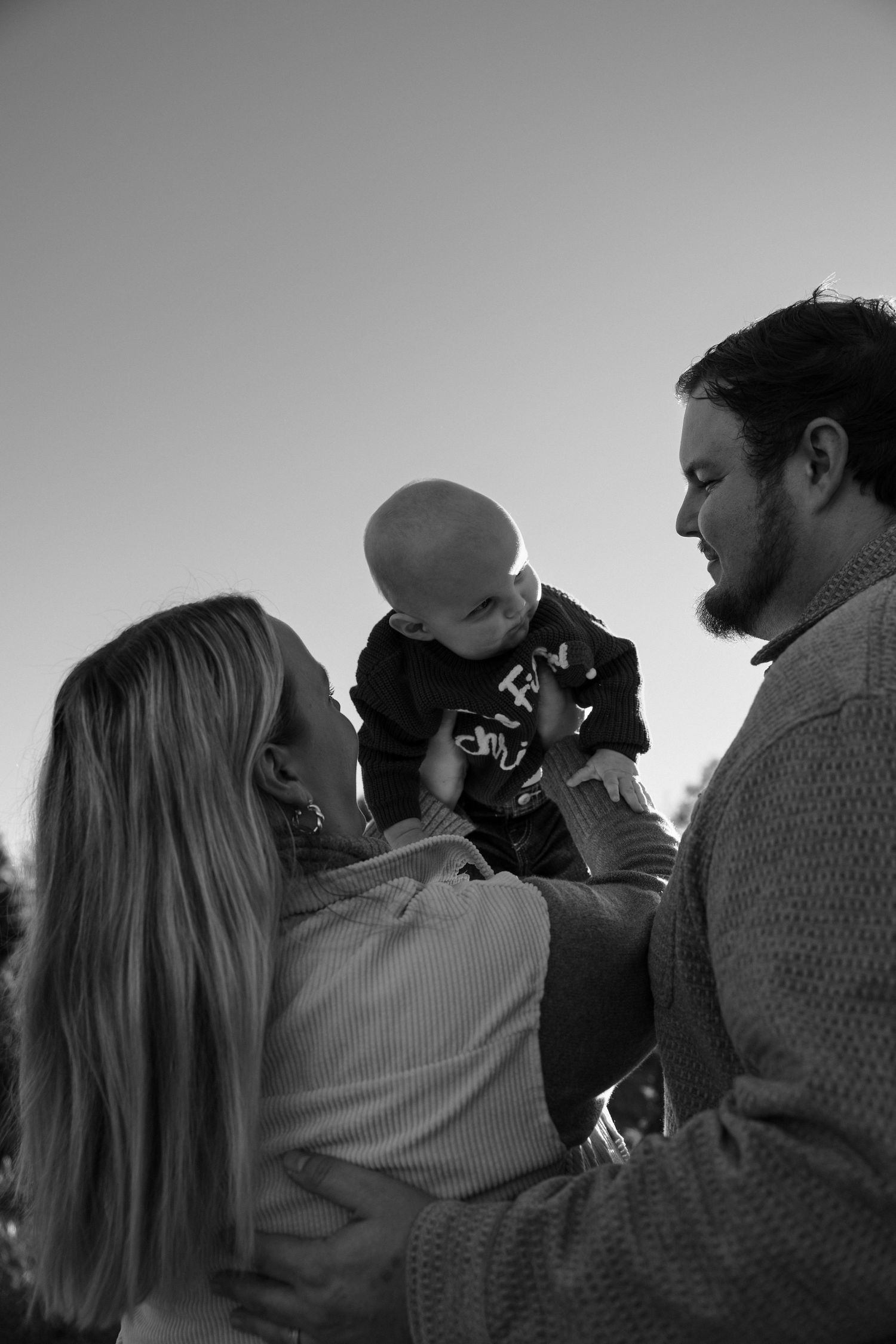 Black and white portrait of family sharing intimate moment together outdoors.