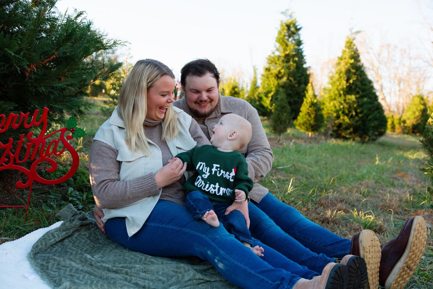 Family relaxing together on blanket during outdoor photo session.
