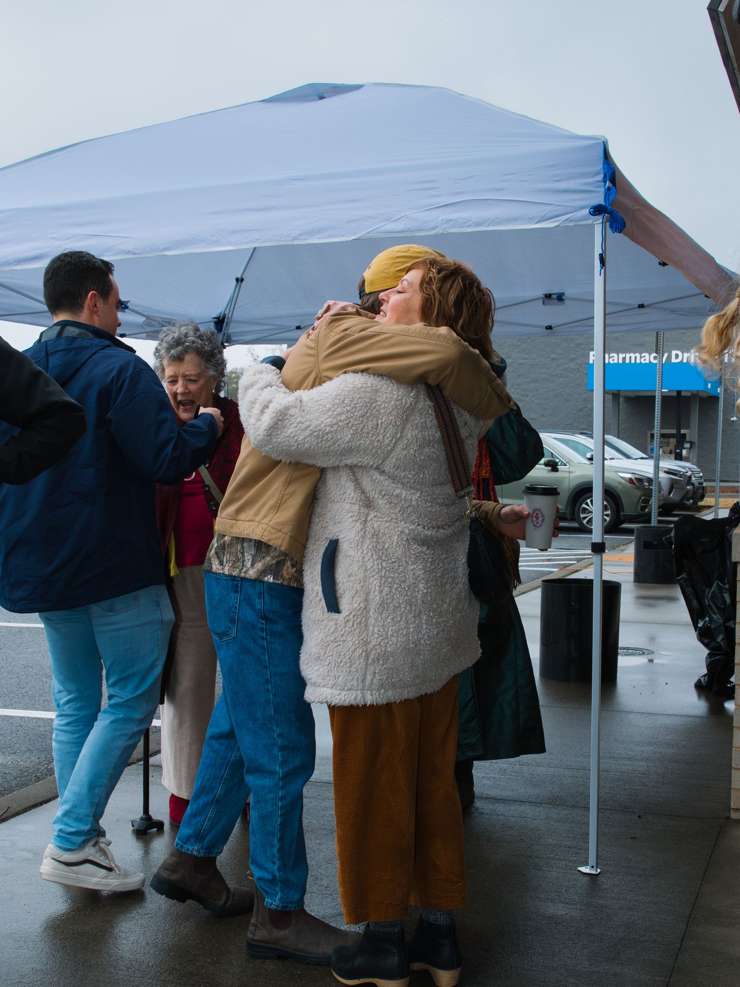 People gathered under blue pop-up tents at an outdoor business event.