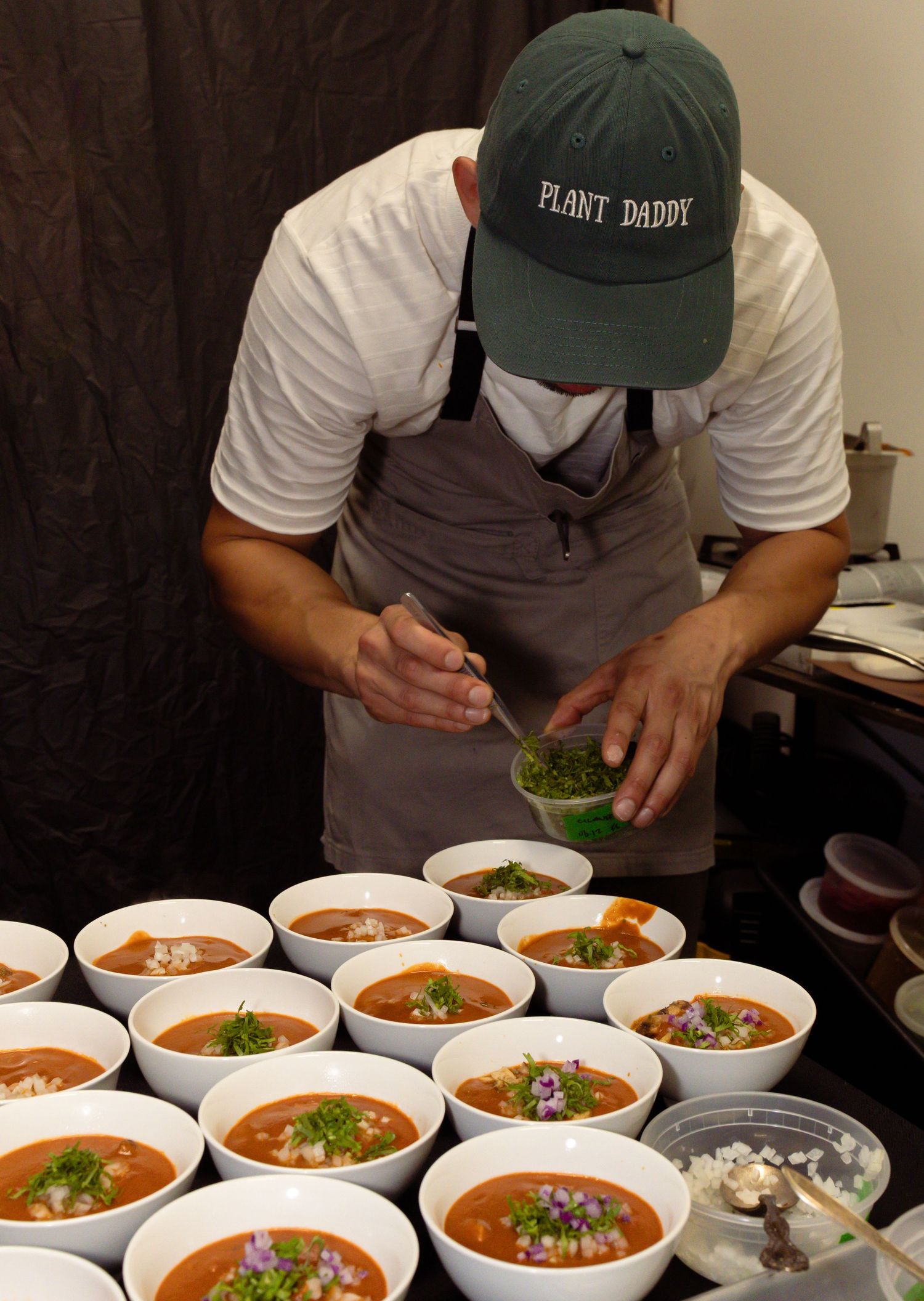 Multiple bowls of steaming soup garnished with fresh herbs being prepared for service.