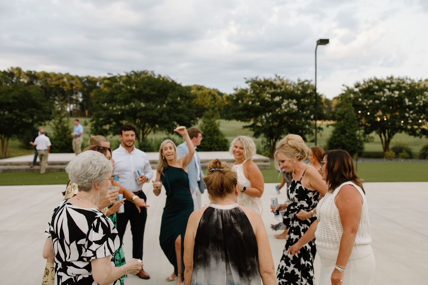 Wedding guests gather outside for celebrations on a cloudy day.