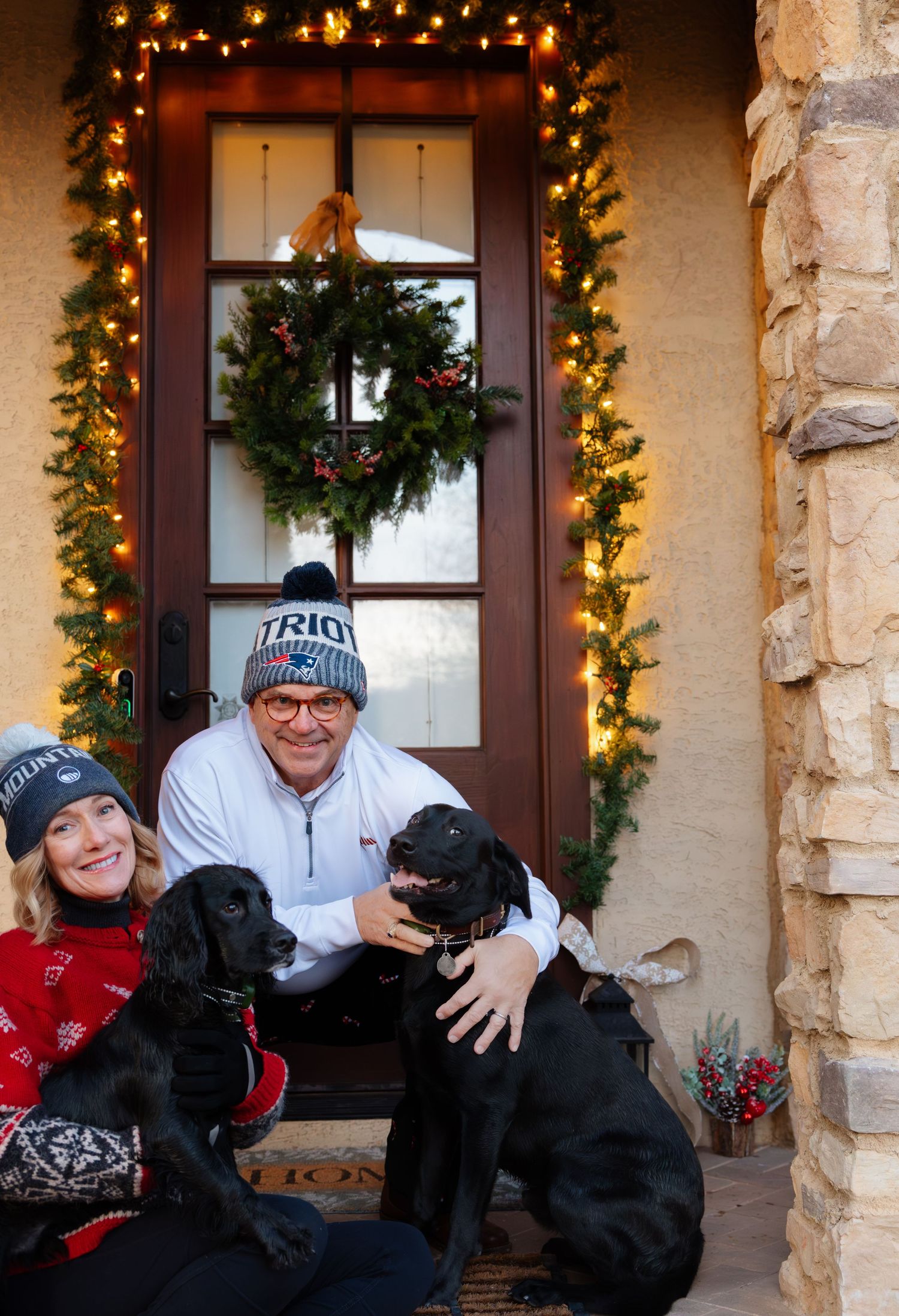 People share a laugh on their Christmas-decorated front porch.