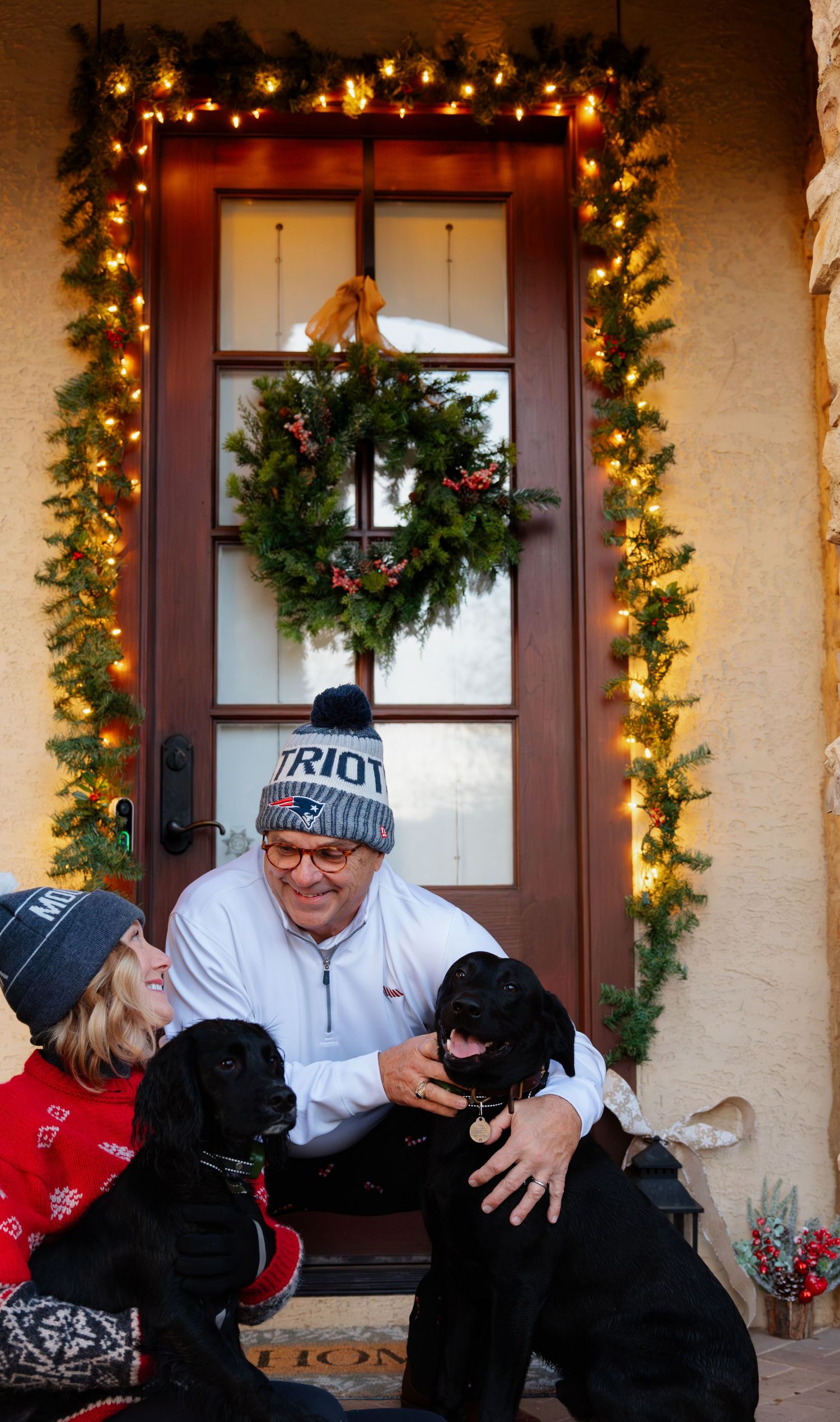 Festive porch scene with Christmas decorations and people laughing together.