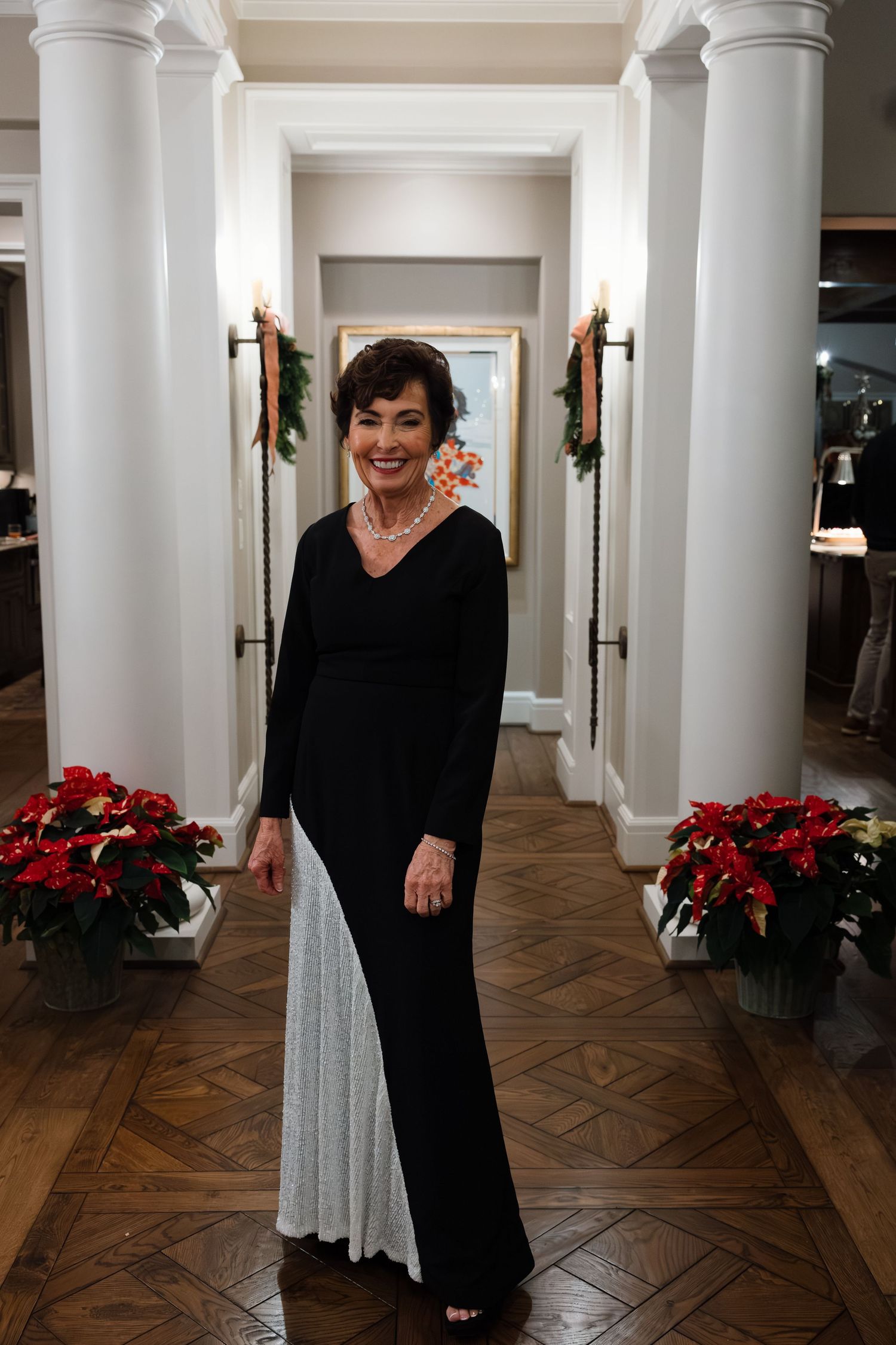 Interior hallway decorated with white columns and red poinsettias for a holiday celebration.