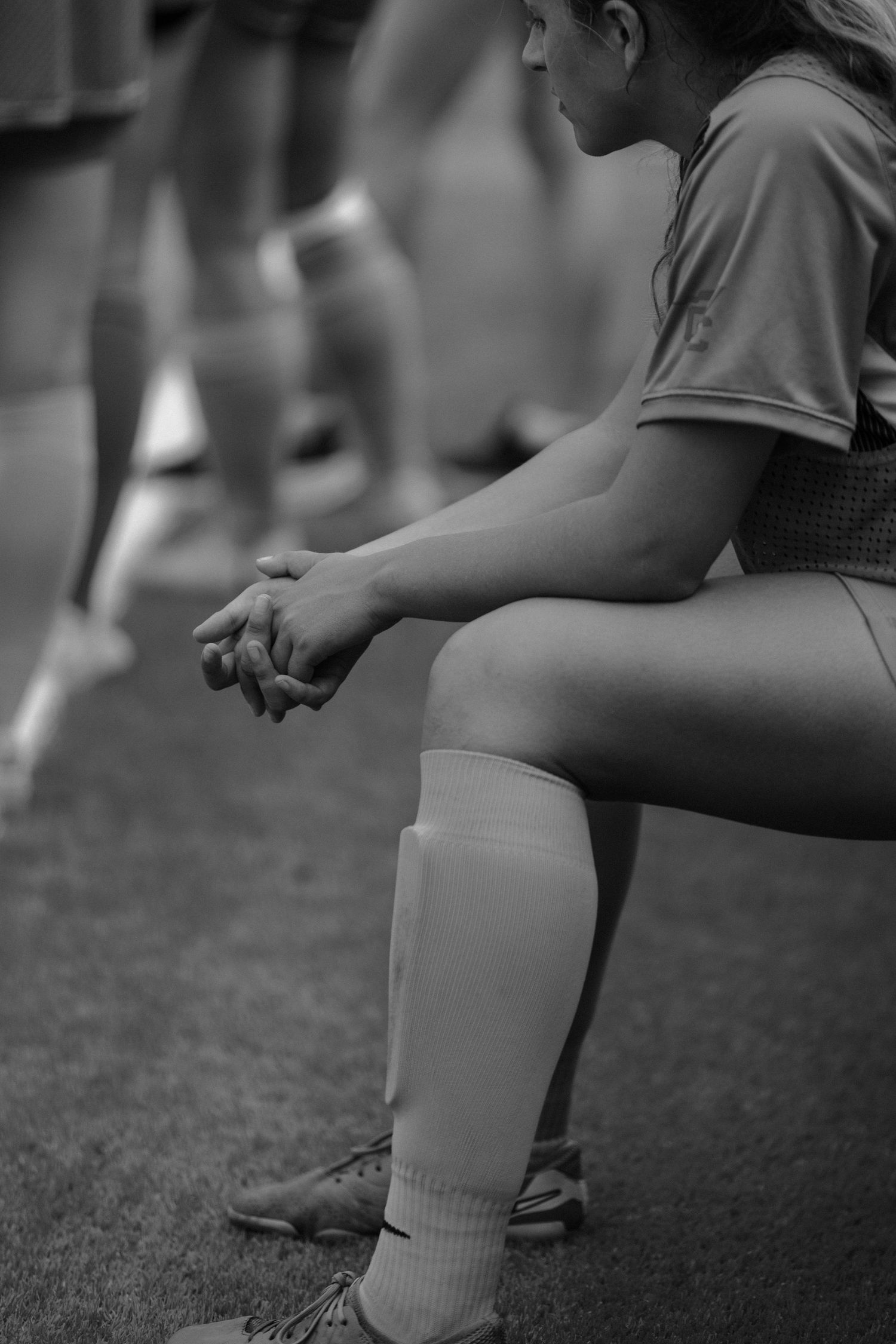 Close-up black and white shot of athletes stretching on field.