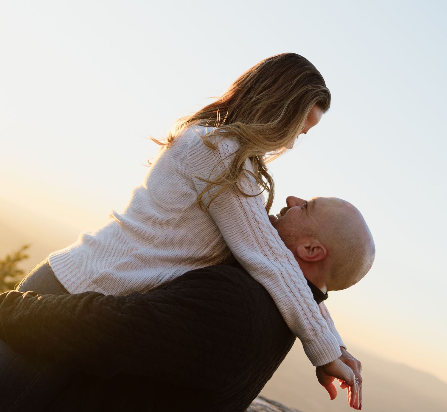 Romantic silhouettes embracing against a bright sky background.