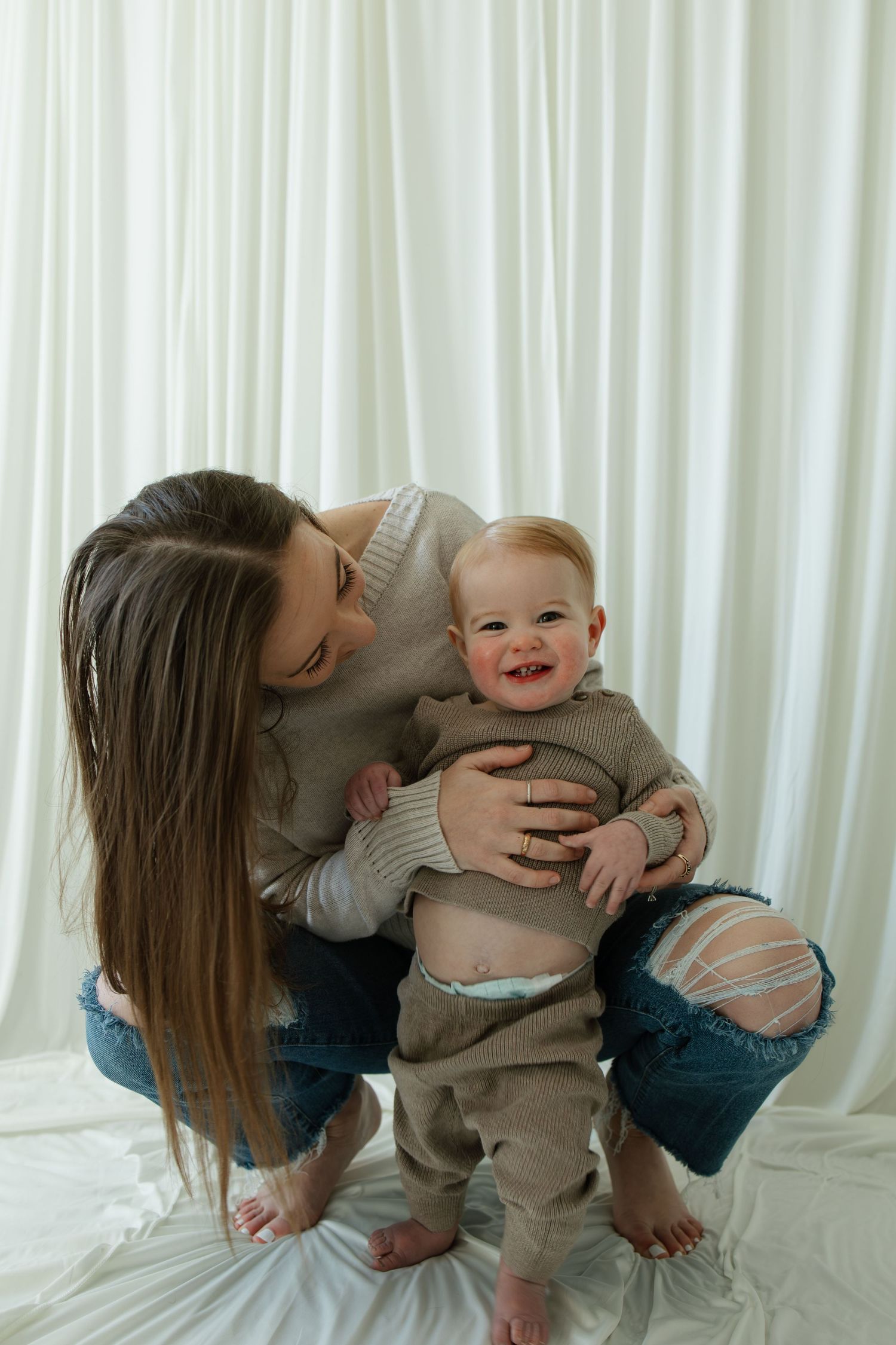 Sweet playful moments between parent and baby on white background.