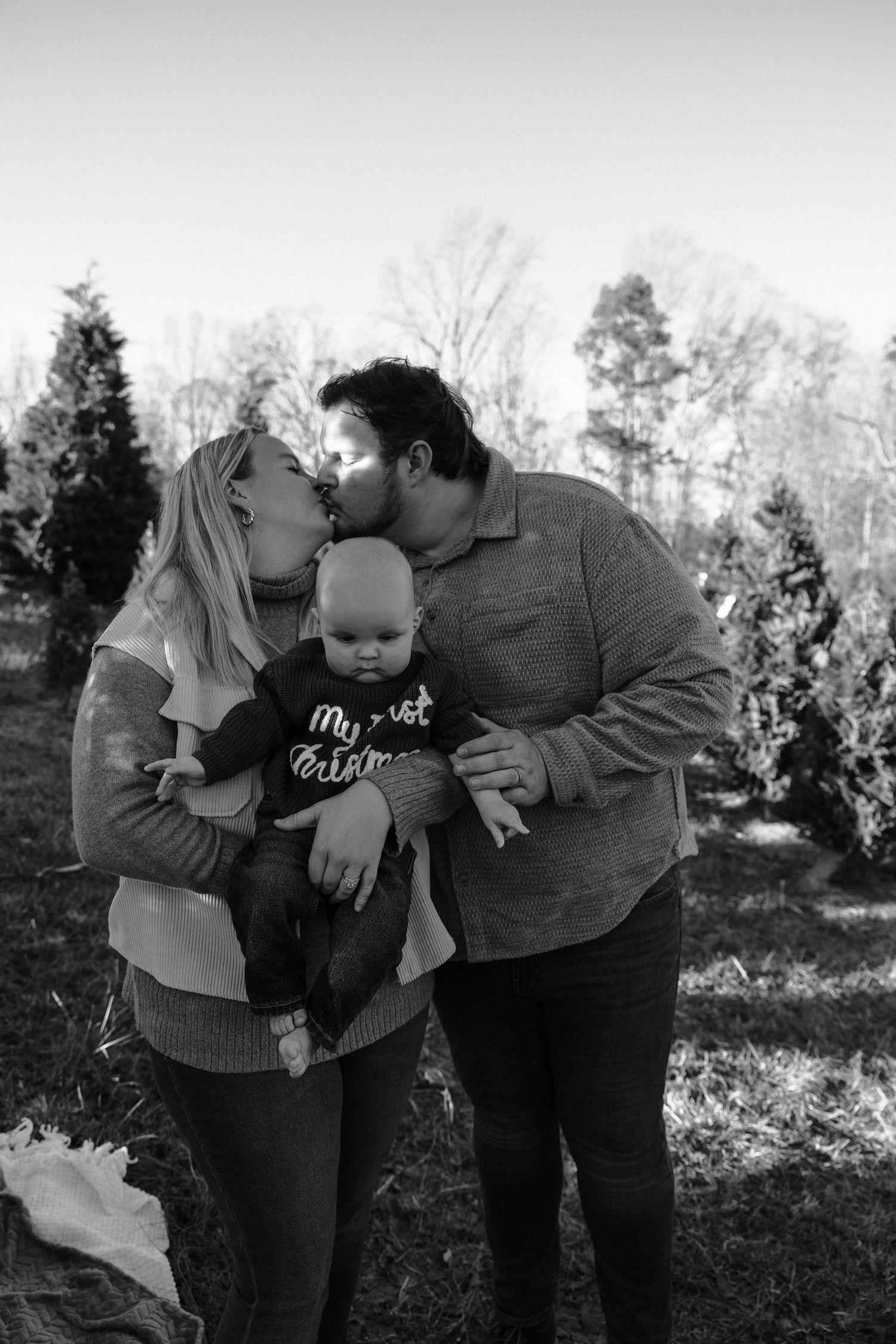 Family sharing tender kisses and embraces in outdoor setting.