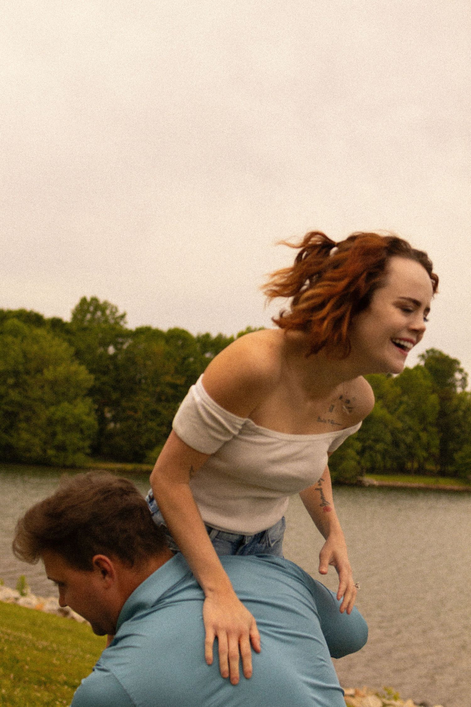 A playful moment captured between a couple by a lakeside on a sunny day.