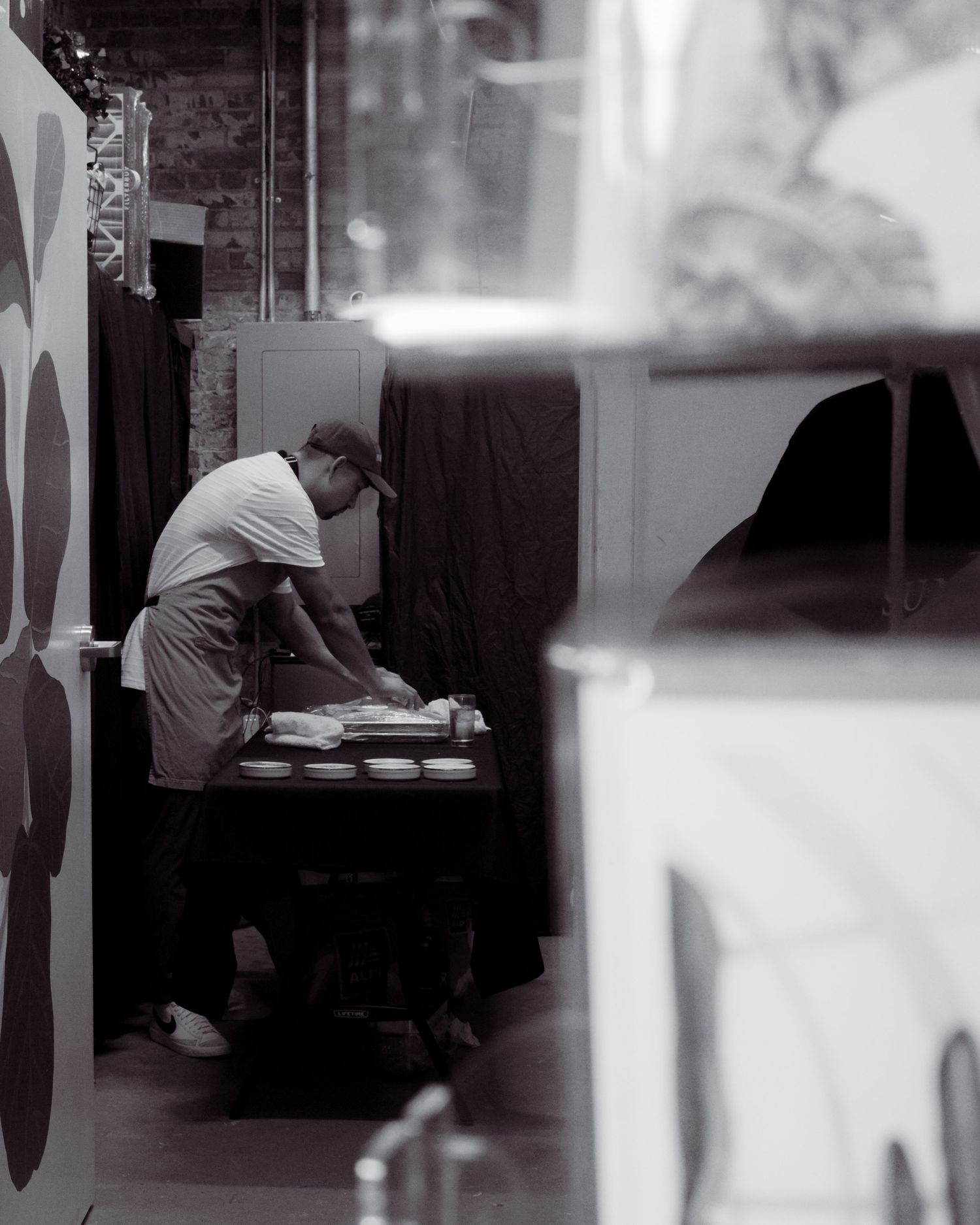 Chef in gray apron preparing food in a modern restaurant kitchen with exposed brick walls.