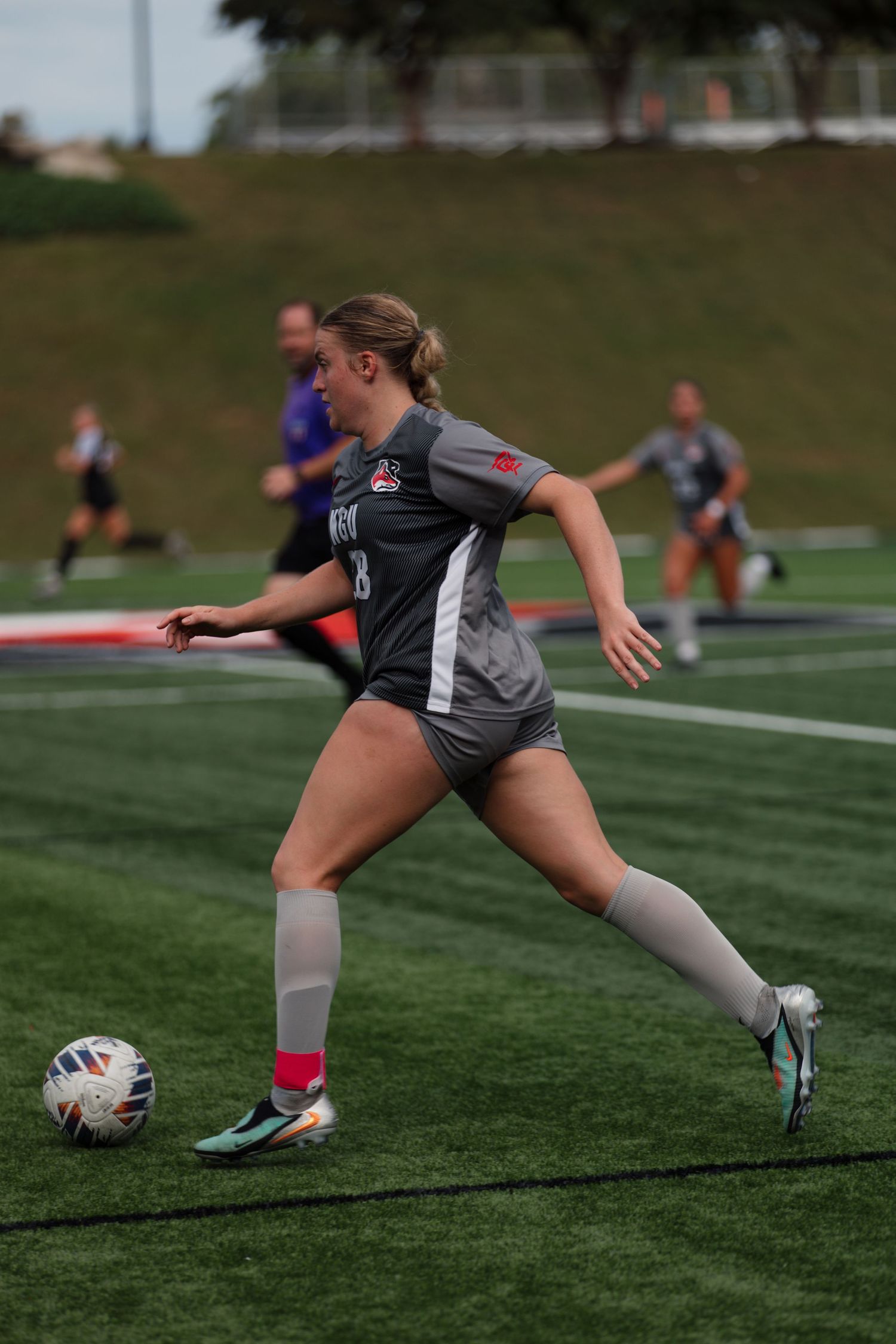 Soccer player chasing after ball during practice drill on turf field.